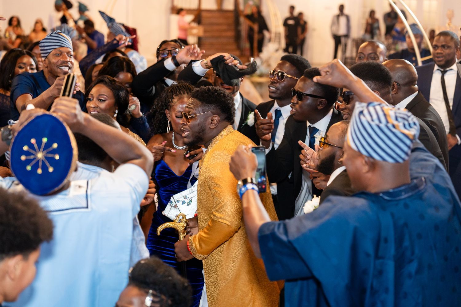 Wedding guests celebrate on the dance floor with energetic dancing and raised arms.