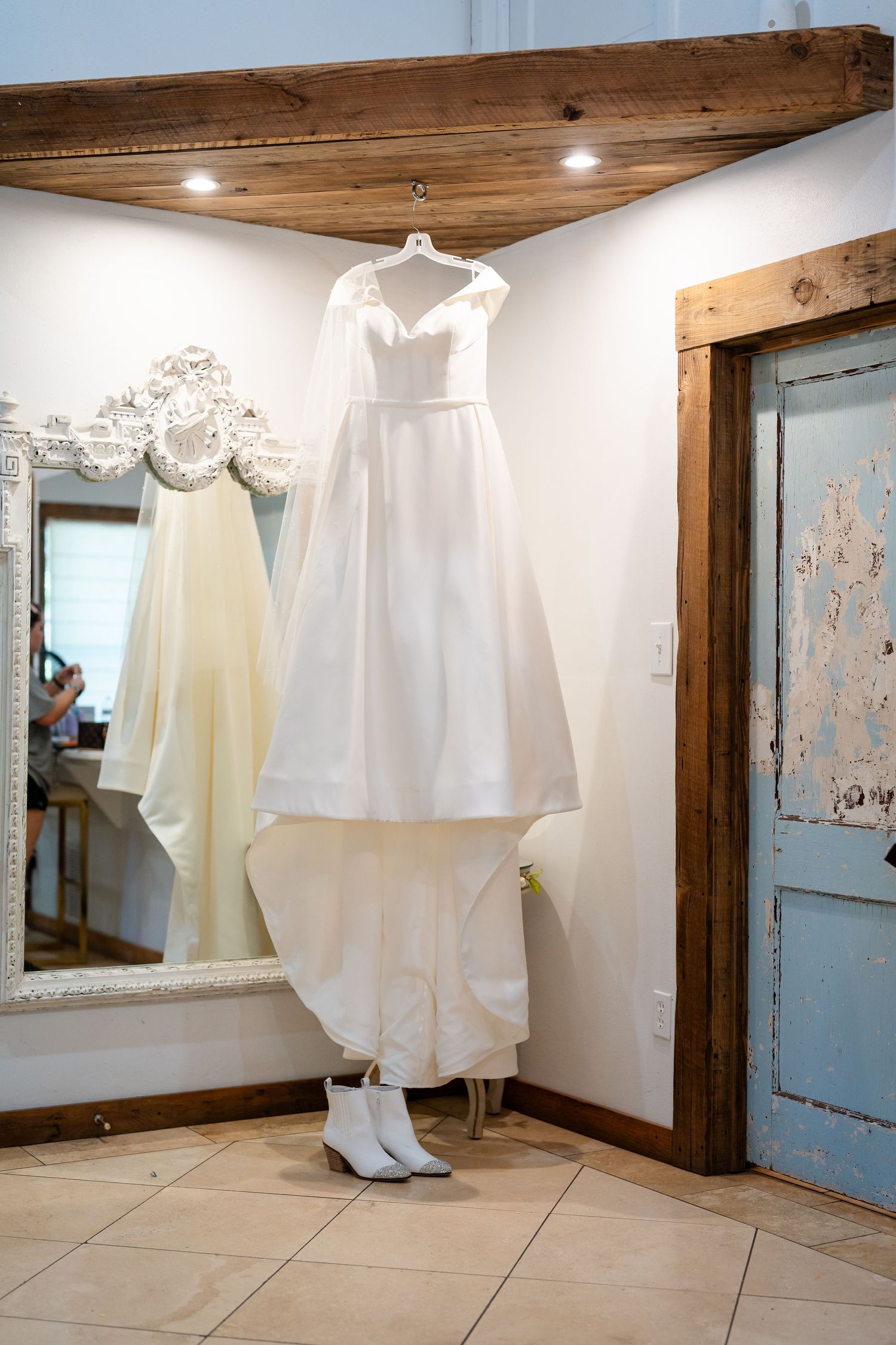 White wedding dresses displayed in a rustic room with wooden ceiling and blue door.