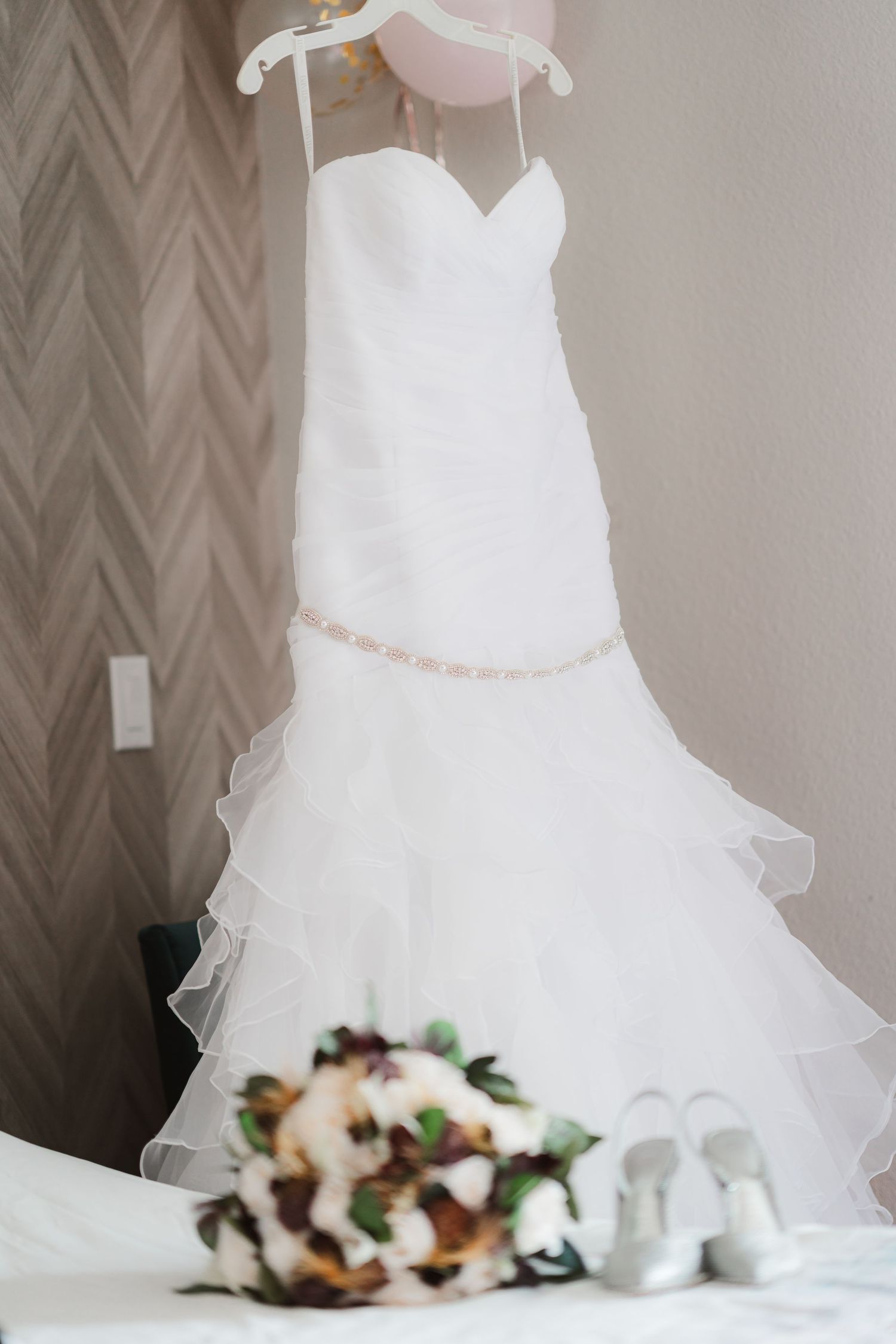 A stunning white wedding dress displayed with floral arrangements and elegant decor.