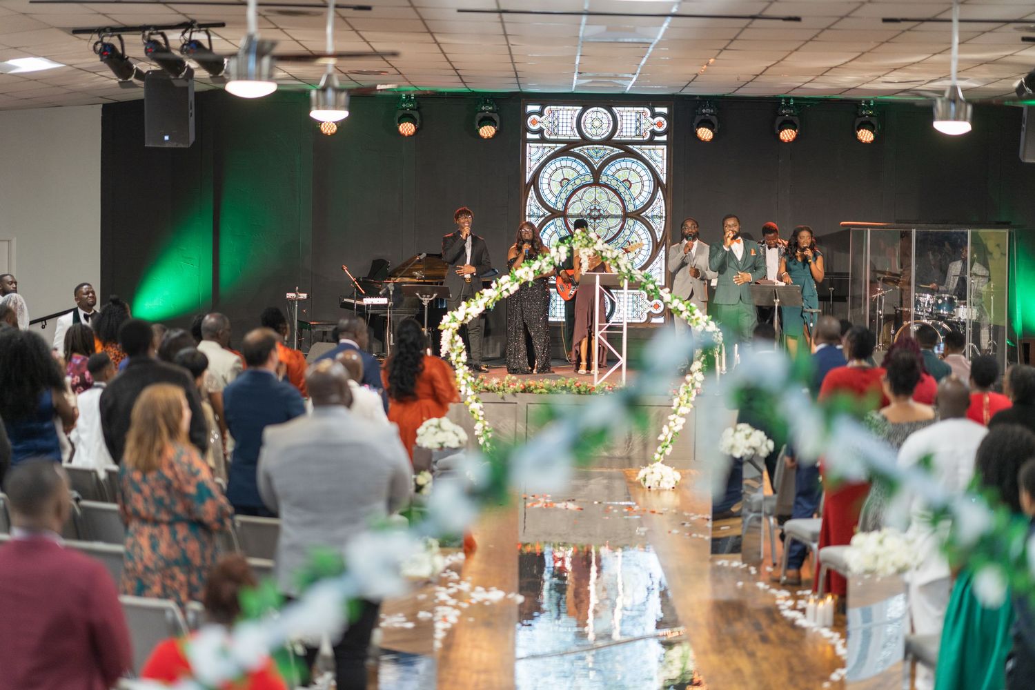 A lively wedding reception venue with stage lighting and band performing for seated guests.