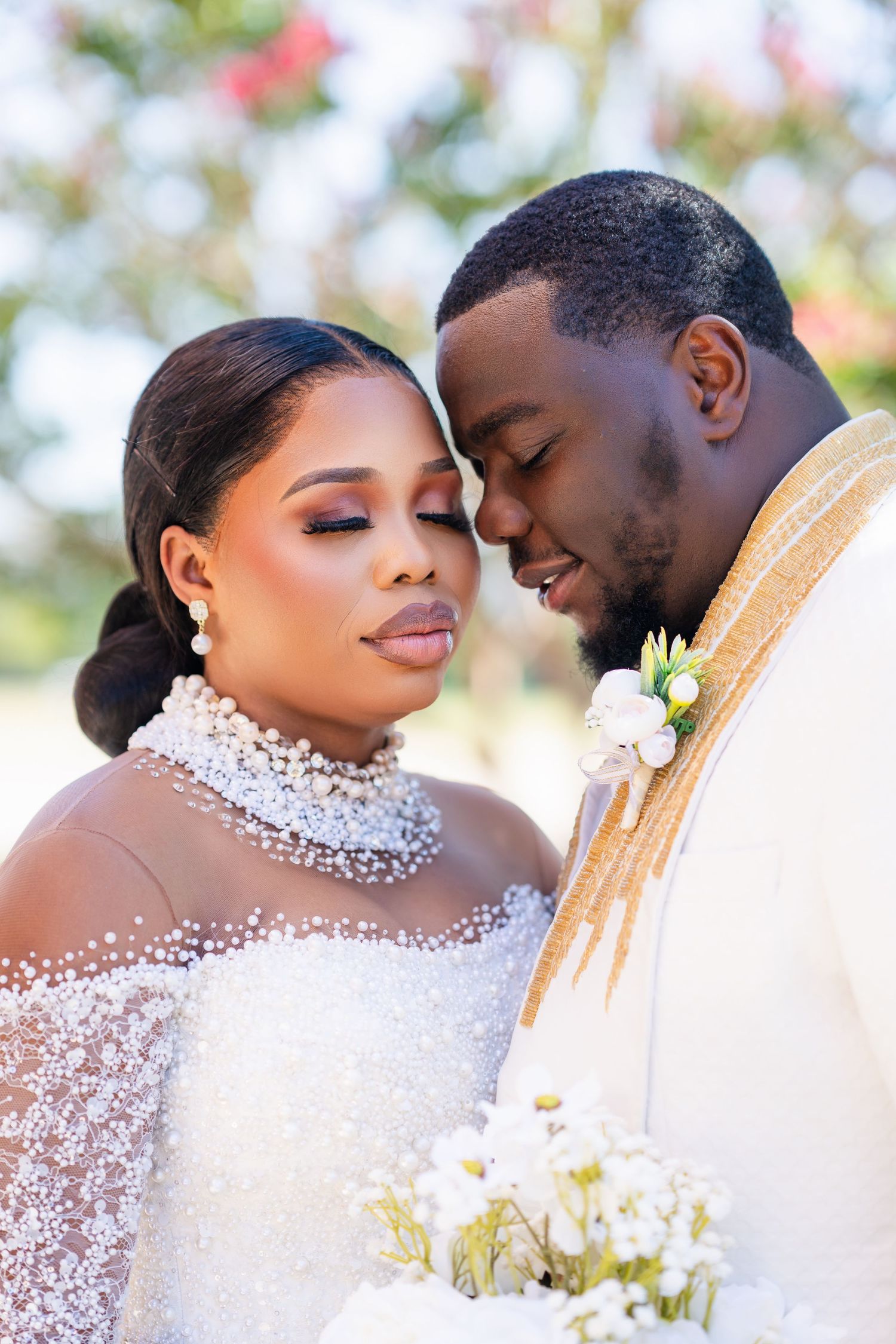 Romantic wedding portrait featuring elegant white attire and floral details in outdoor garden setting.