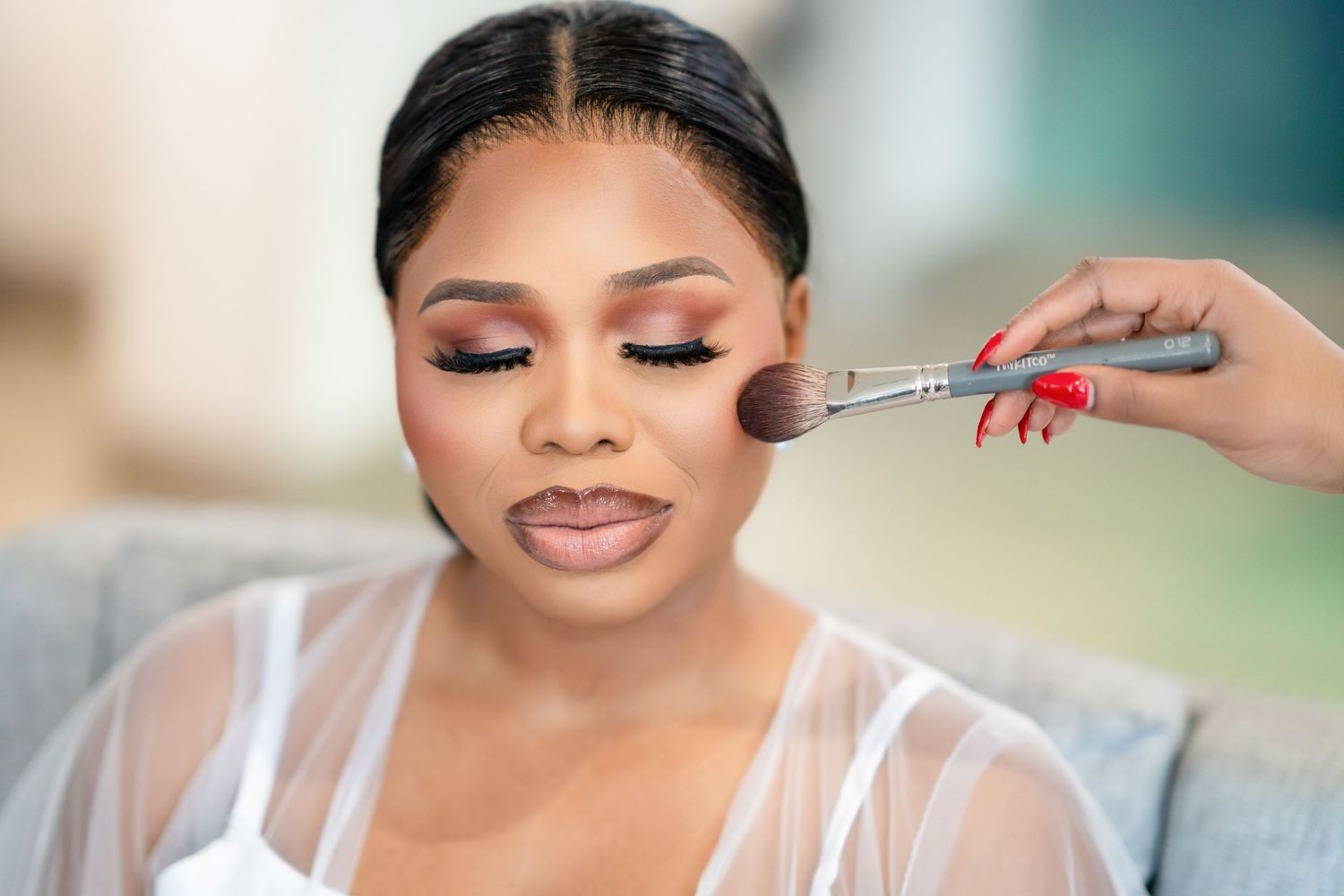 Bride getting professional makeup applied during wedding preparation.