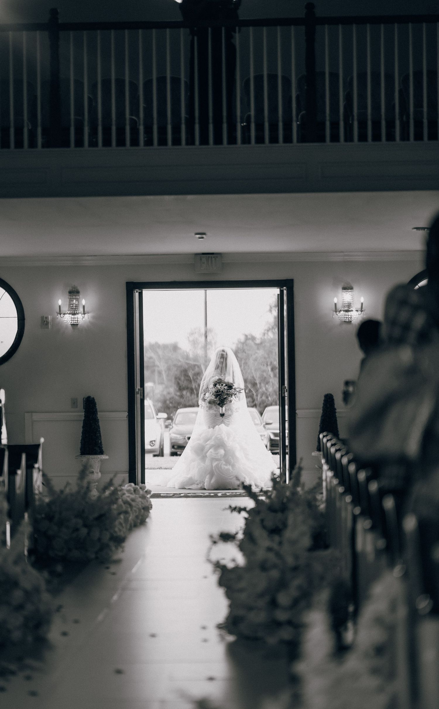 A dramatic black and white silhouette of a wedding venue interior with large windows.