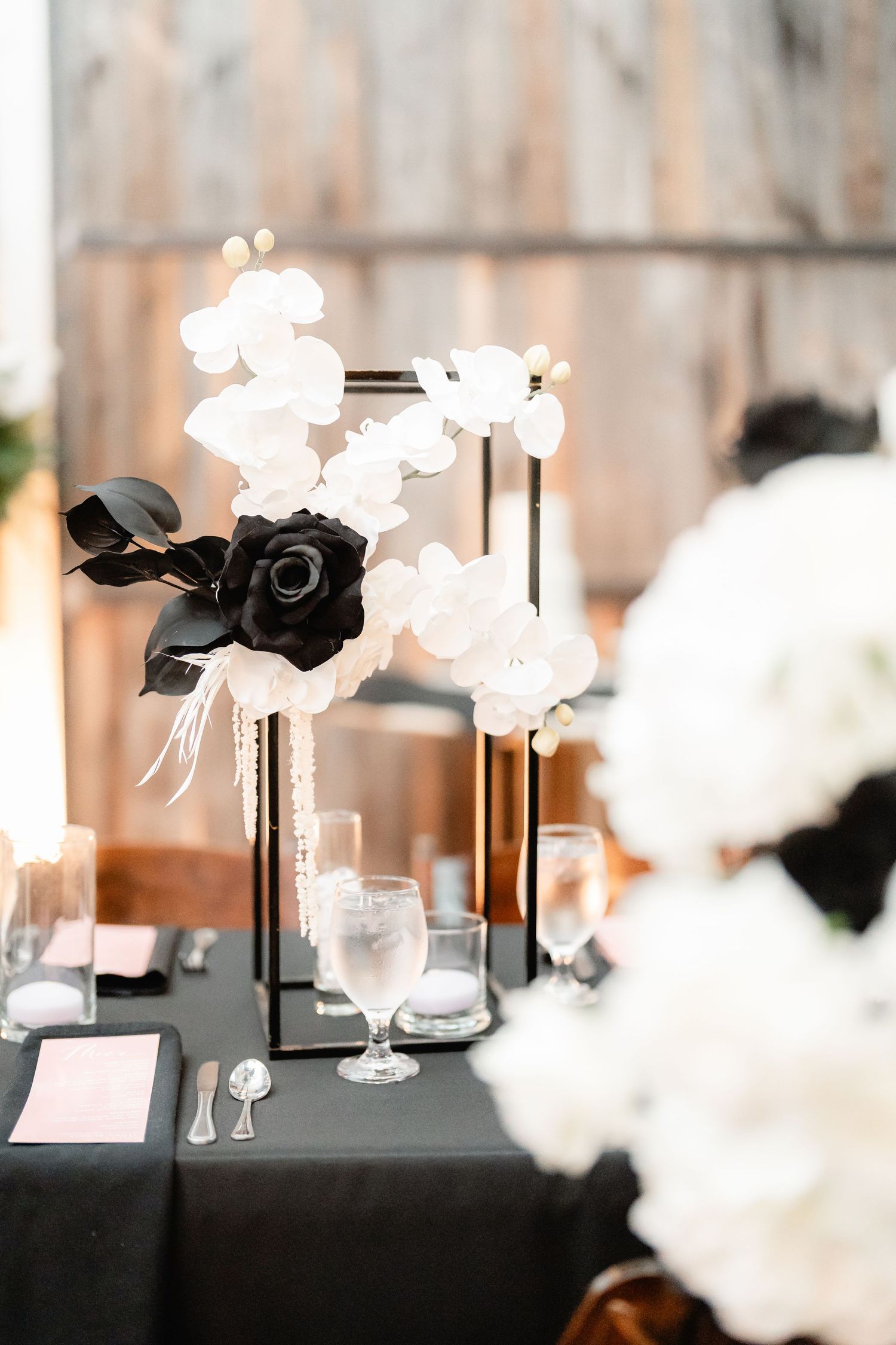 Wedding reception table decor featuring black and white floral centerpieces with elegant lighting.