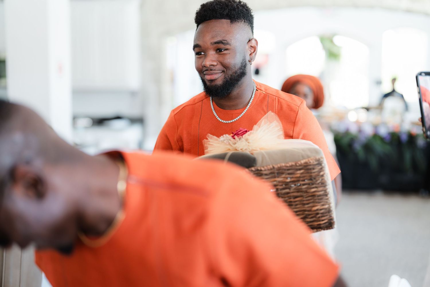 Wedding guests in orange shirts celebrating and laughing together at an indoor reception.