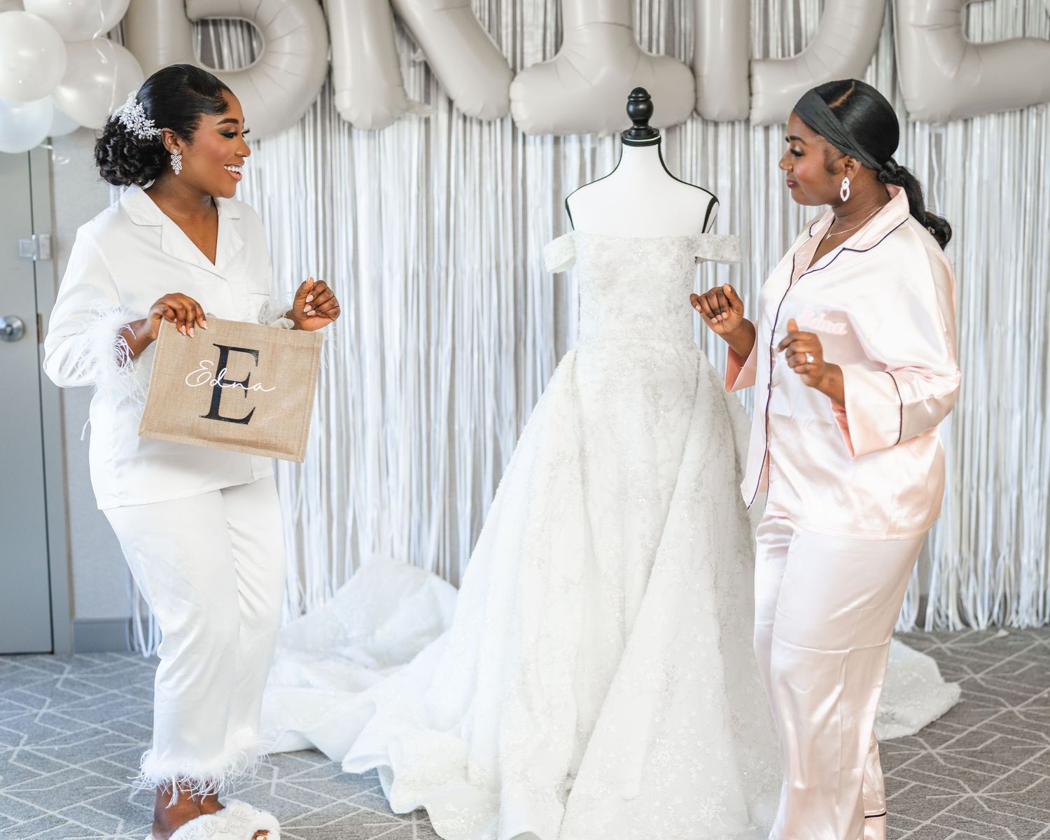 Two people in white robes celebrating near a wedding dress display with champagne.