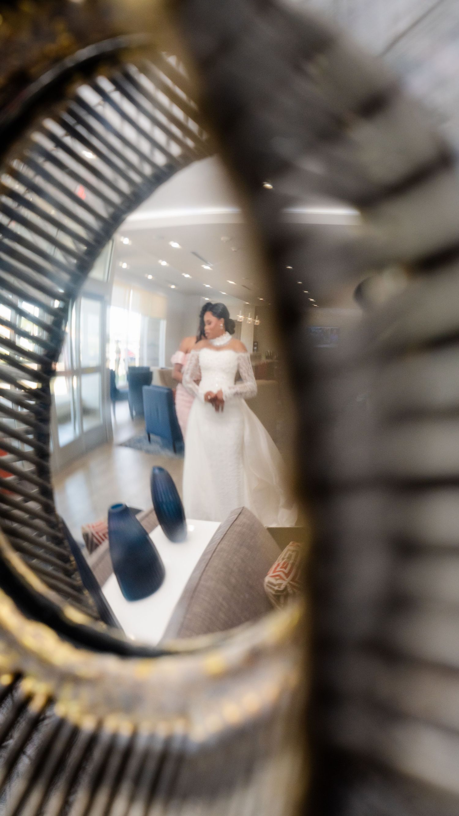 Artistic fisheye lens view of a bride in a flowing white dress walking through a modern hallway.