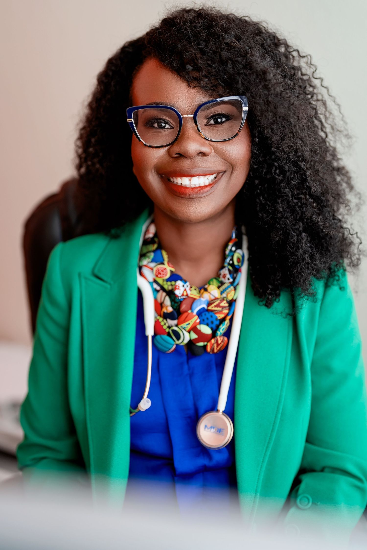Professional portrait series showing bright green blazer with blue top and colorful floral necklace against light background.