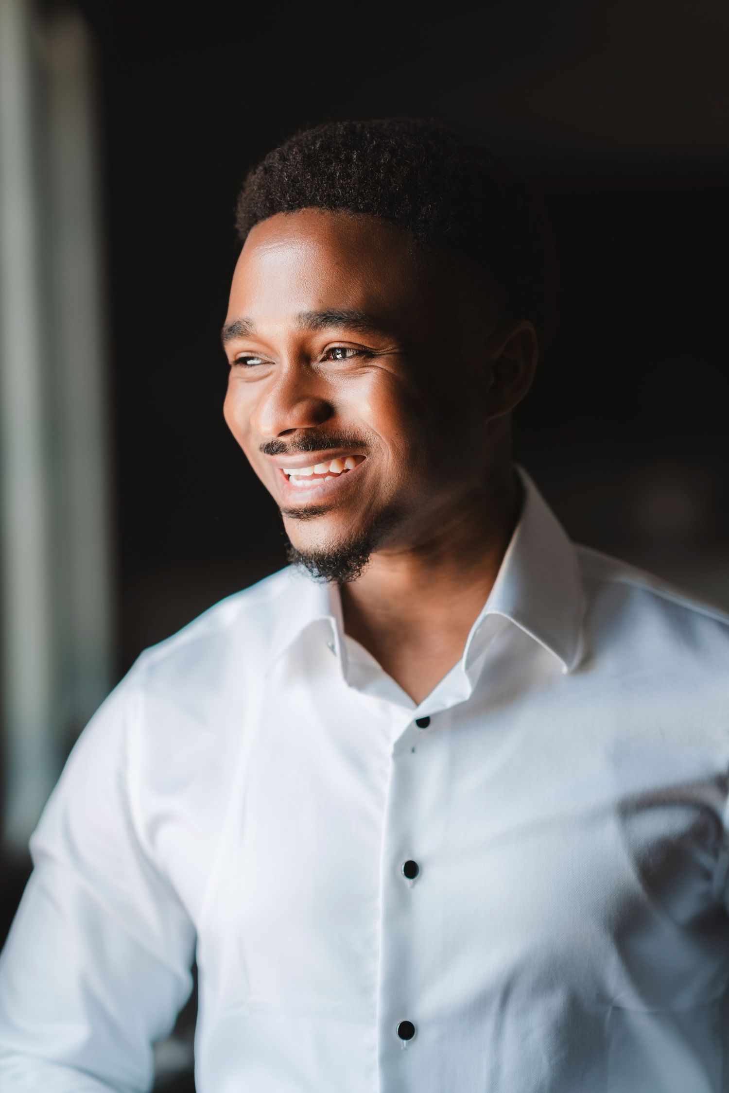 Close-up portrait shots in formal white dress shirt against dark background.