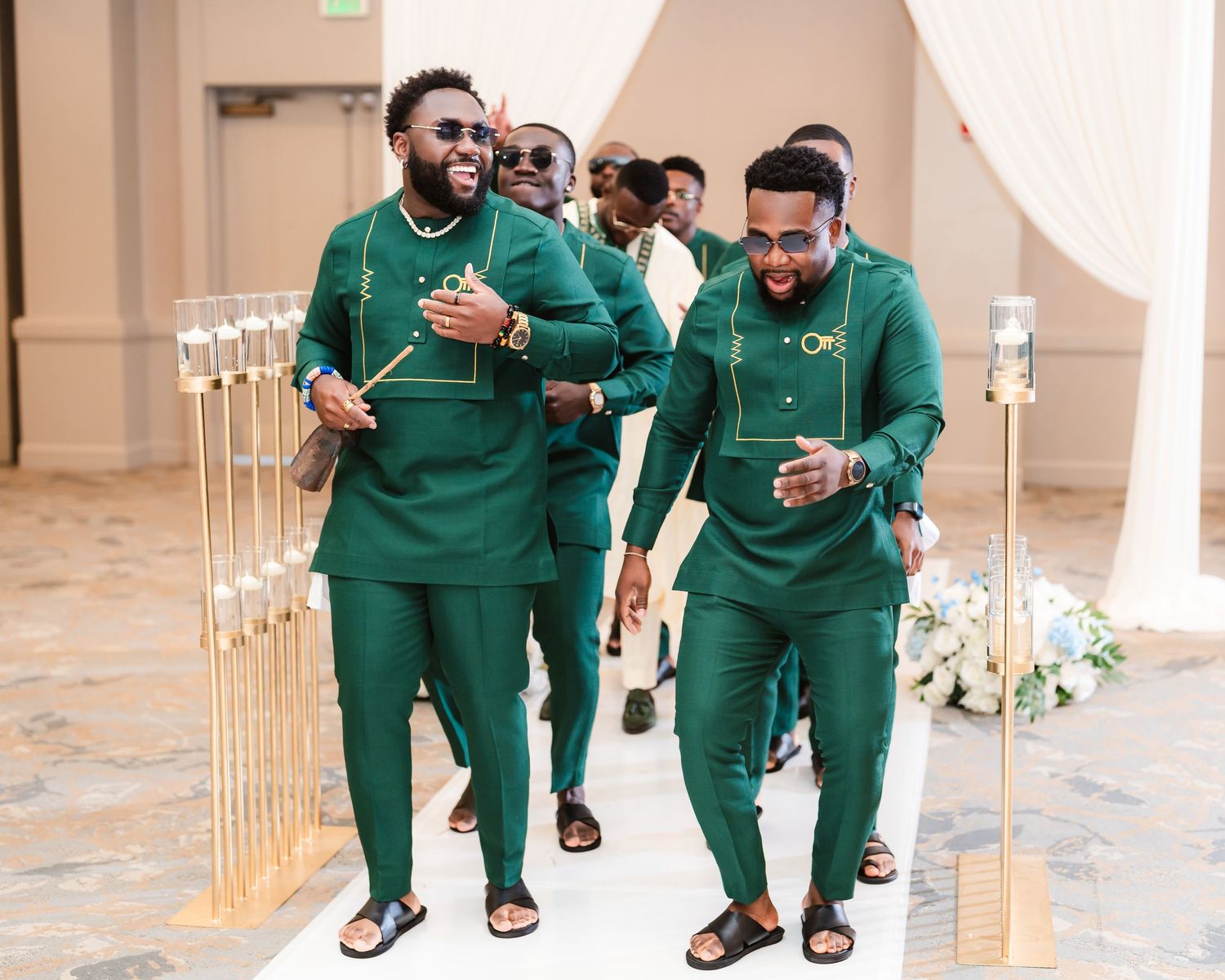 Groomsmen in matching emerald green suits posing together at wedding venue.
