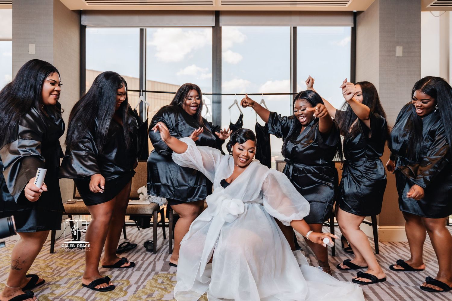 Wedding party in black and white attire posing together in a modern indoor venue.