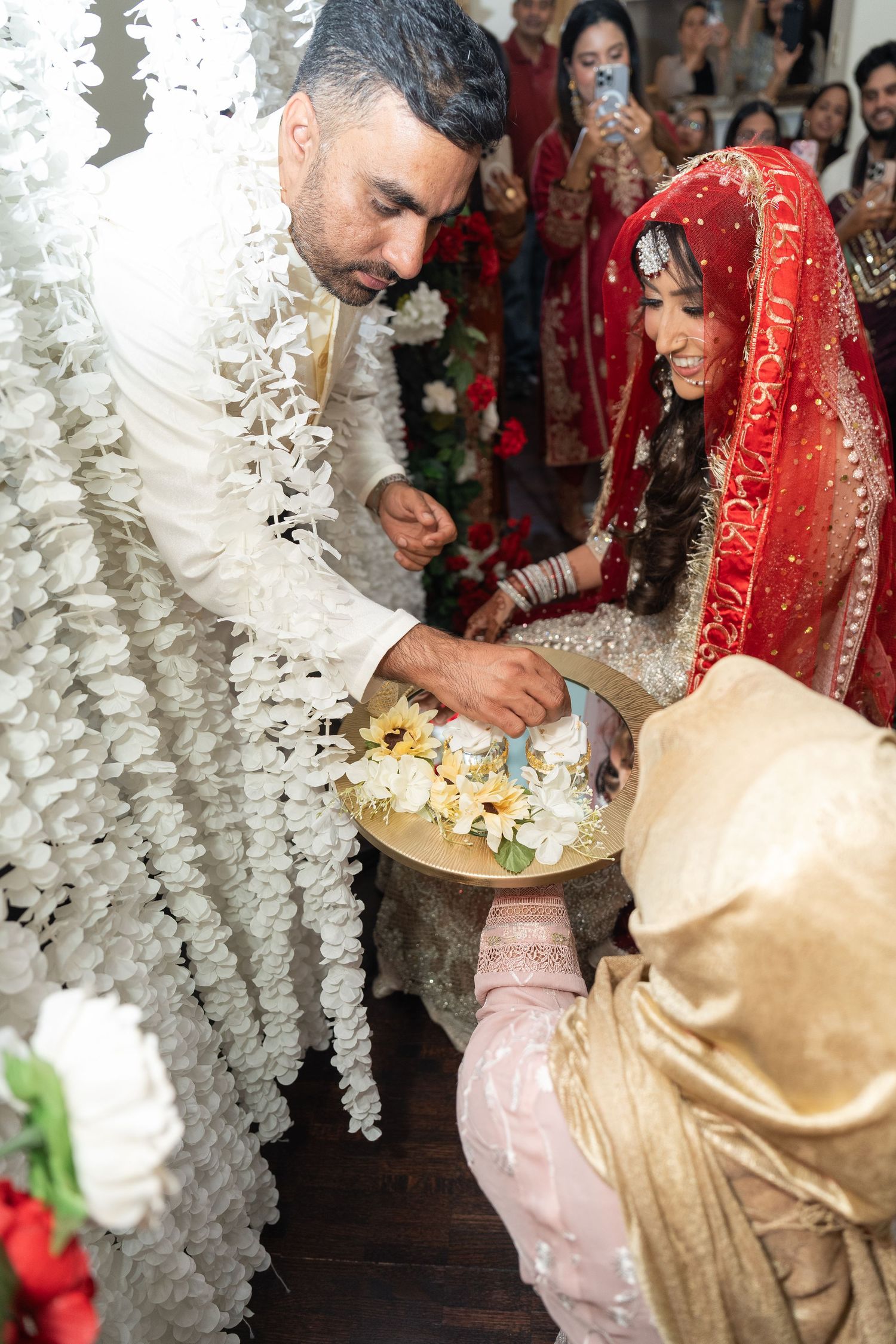 Wedding ceremony signing moment with hanging white floral decorations and traditional attire.