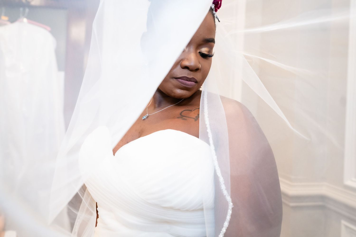 A person in a white dress and veil poses against a white background during a bridal photoshoot.
