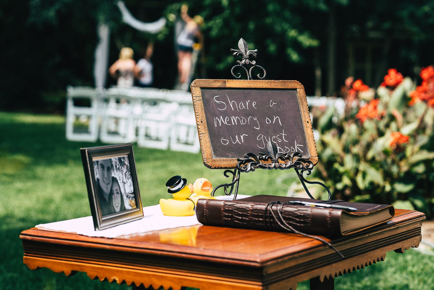 Wedding guest book table setup outdoors with chalkboard sign and vintage decor.