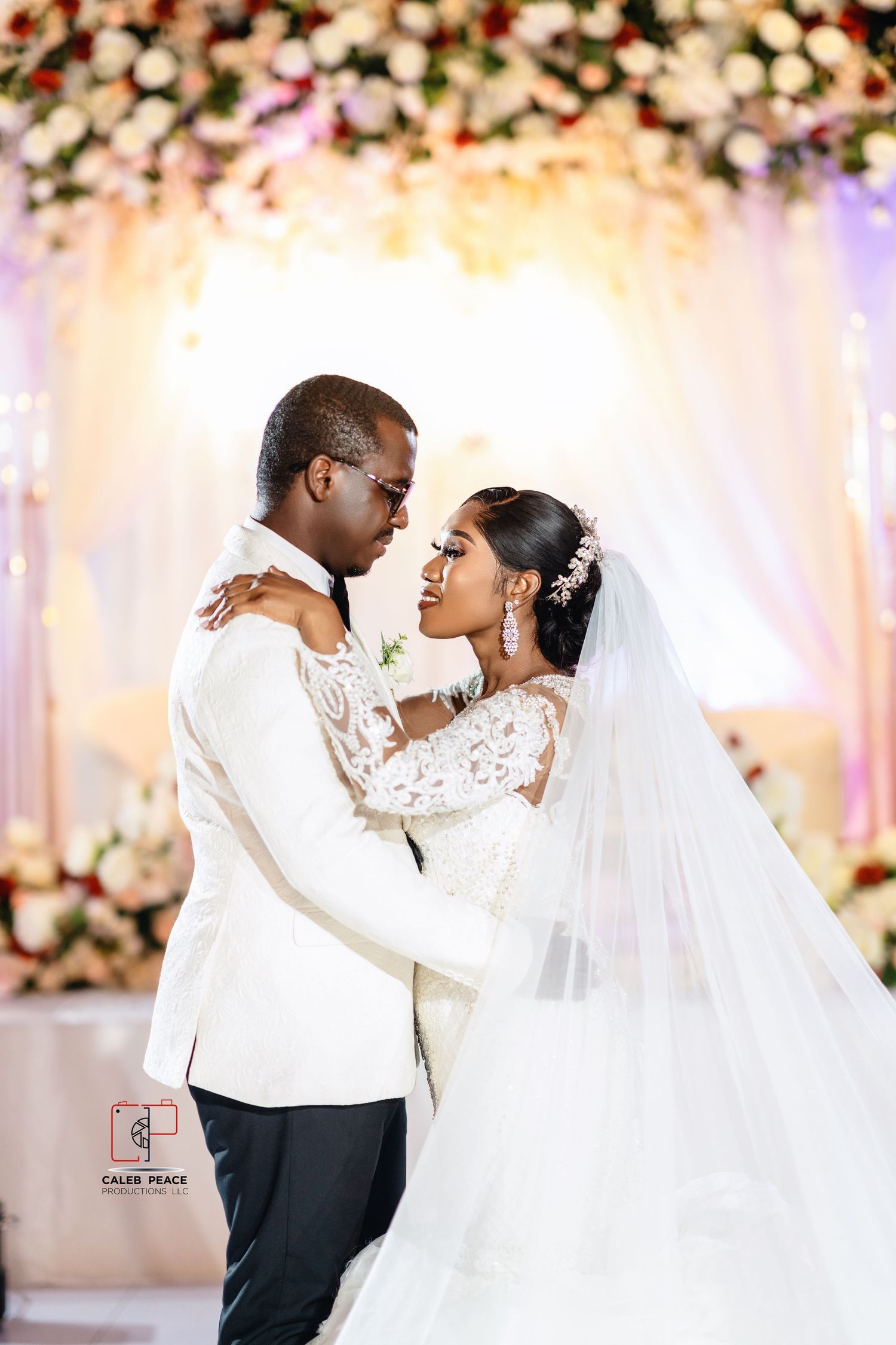 Couple sharing intimate moments on their wedding day in a beautifully decorated venue with floral backdrops.