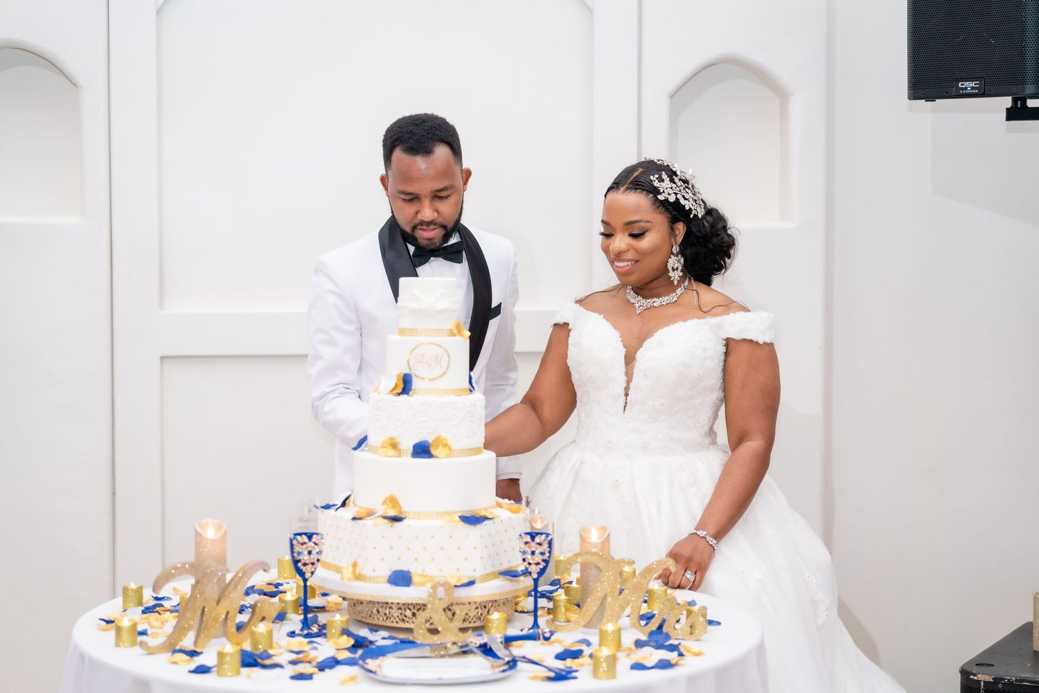 A couple in formal white attire enjoys their wedding reception meal at an elegant table setting.