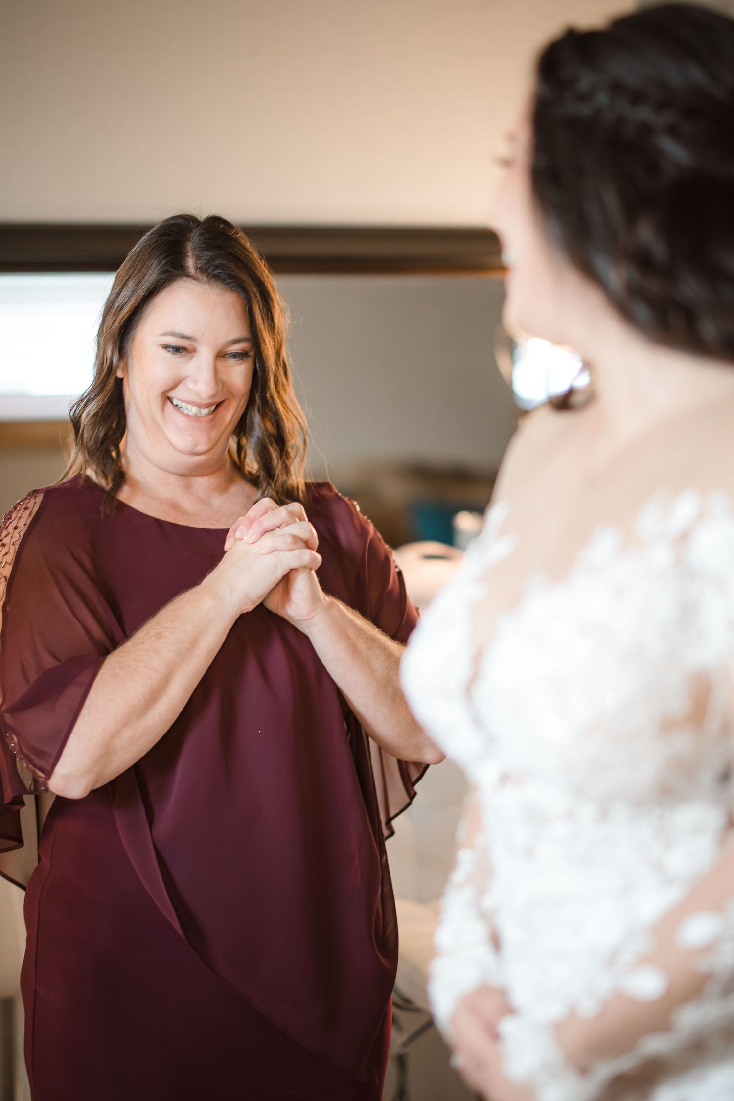 Emotional candid moments captured during wedding preparations in a warm-toned indoor setting.