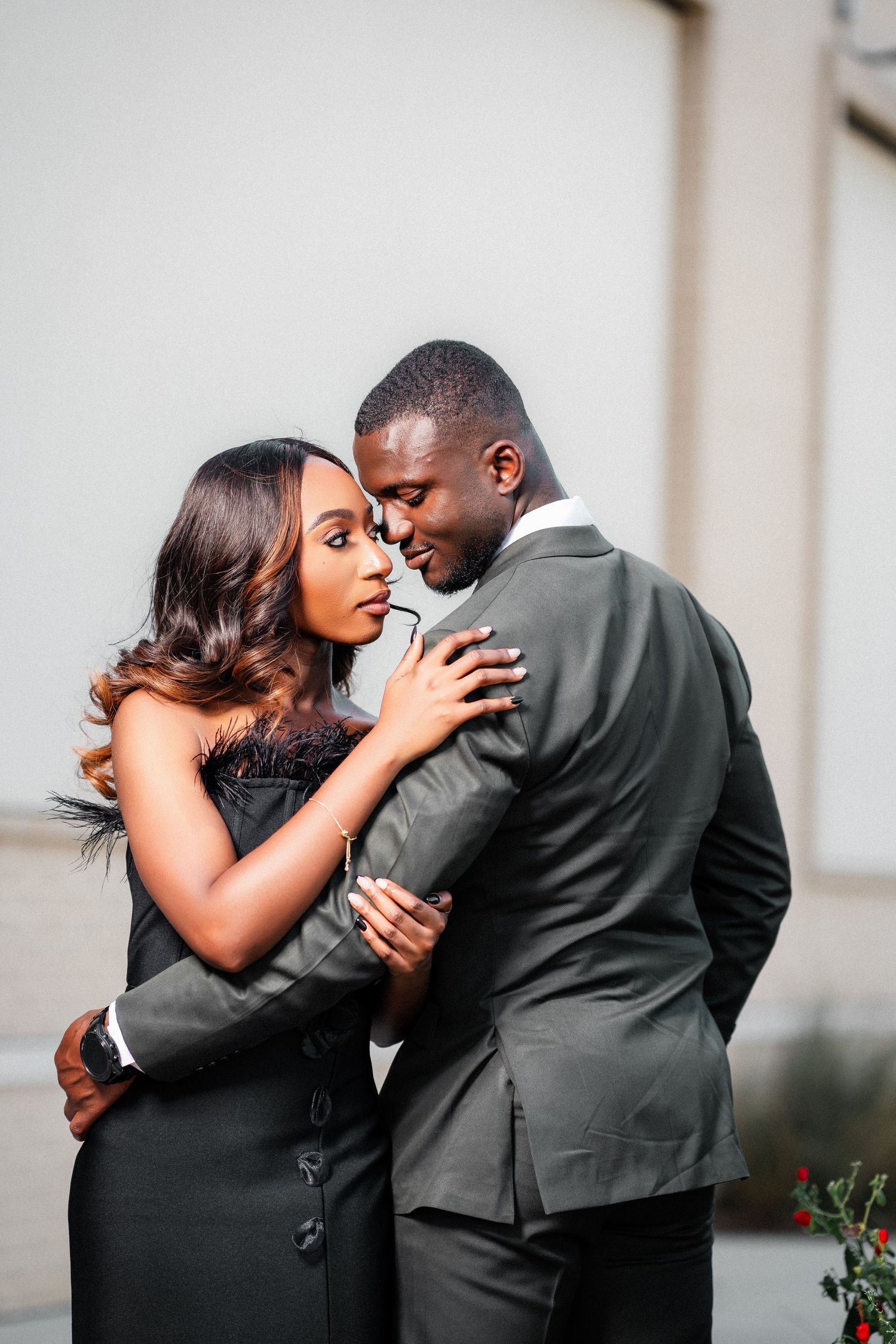 An intimate portrait of a couple in formal wear sharing a tender moment against a light background.