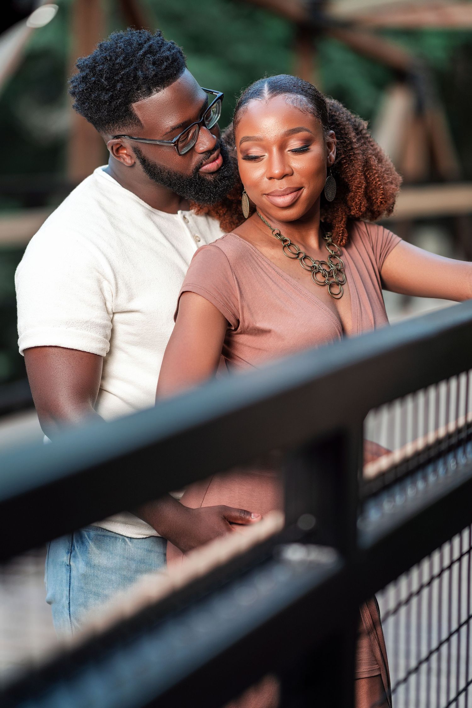 A couple embraces on a bridge during a romantic outdoor photo session.