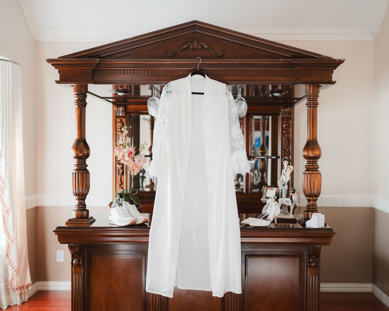 Classic wooden dressers and mirrors line a wall, with a white wedding dress displayed.