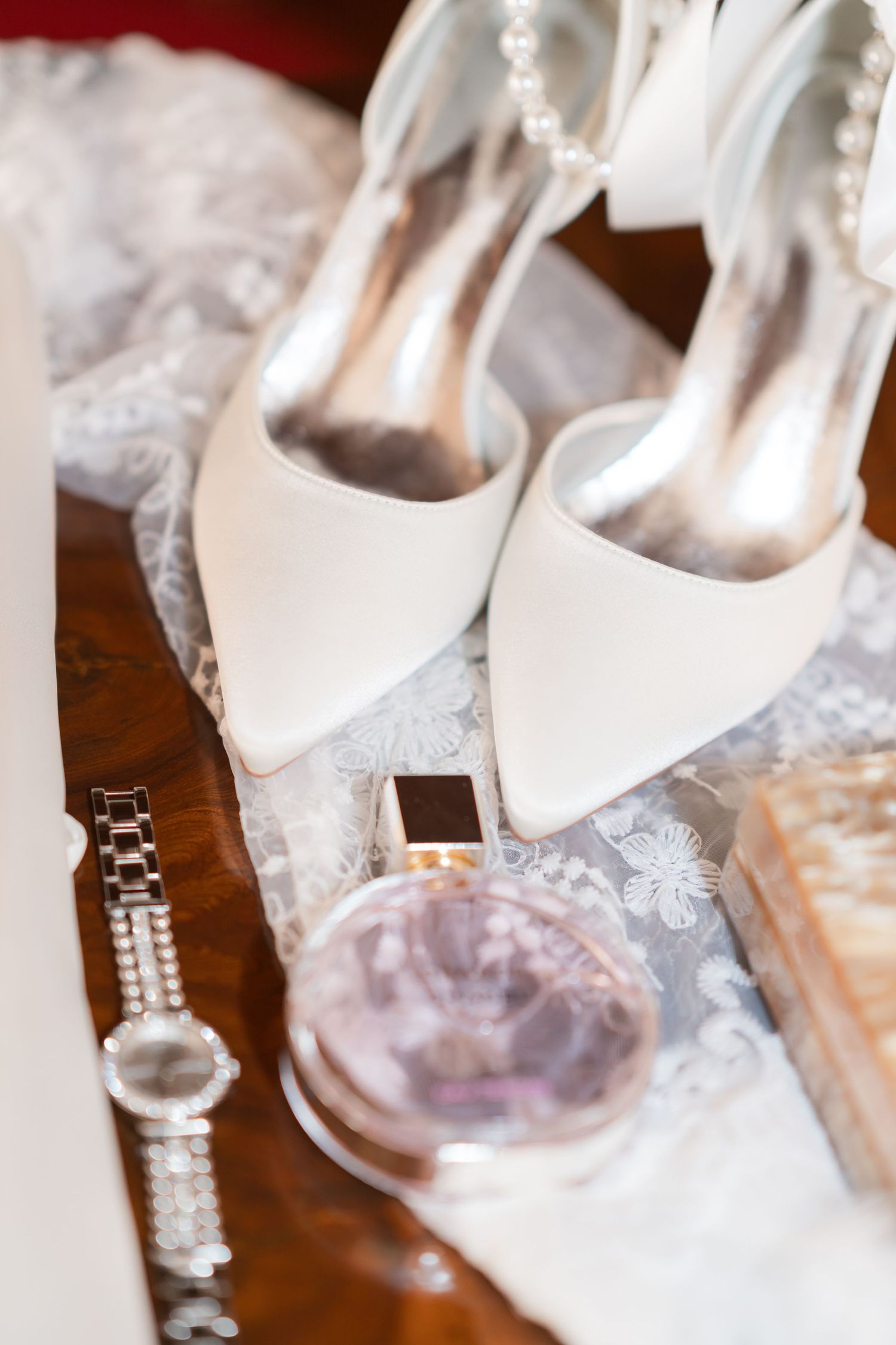 White wedding heels and jewelry accessories arranged on a textured surface.