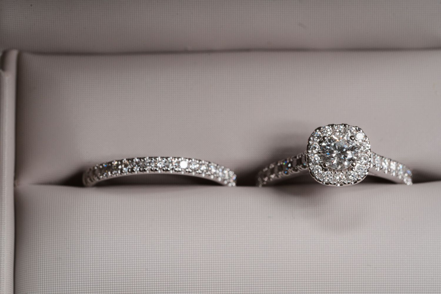 Collection of elegant diamond wedding rings and bridal jewelry displayed on a light gray surface.