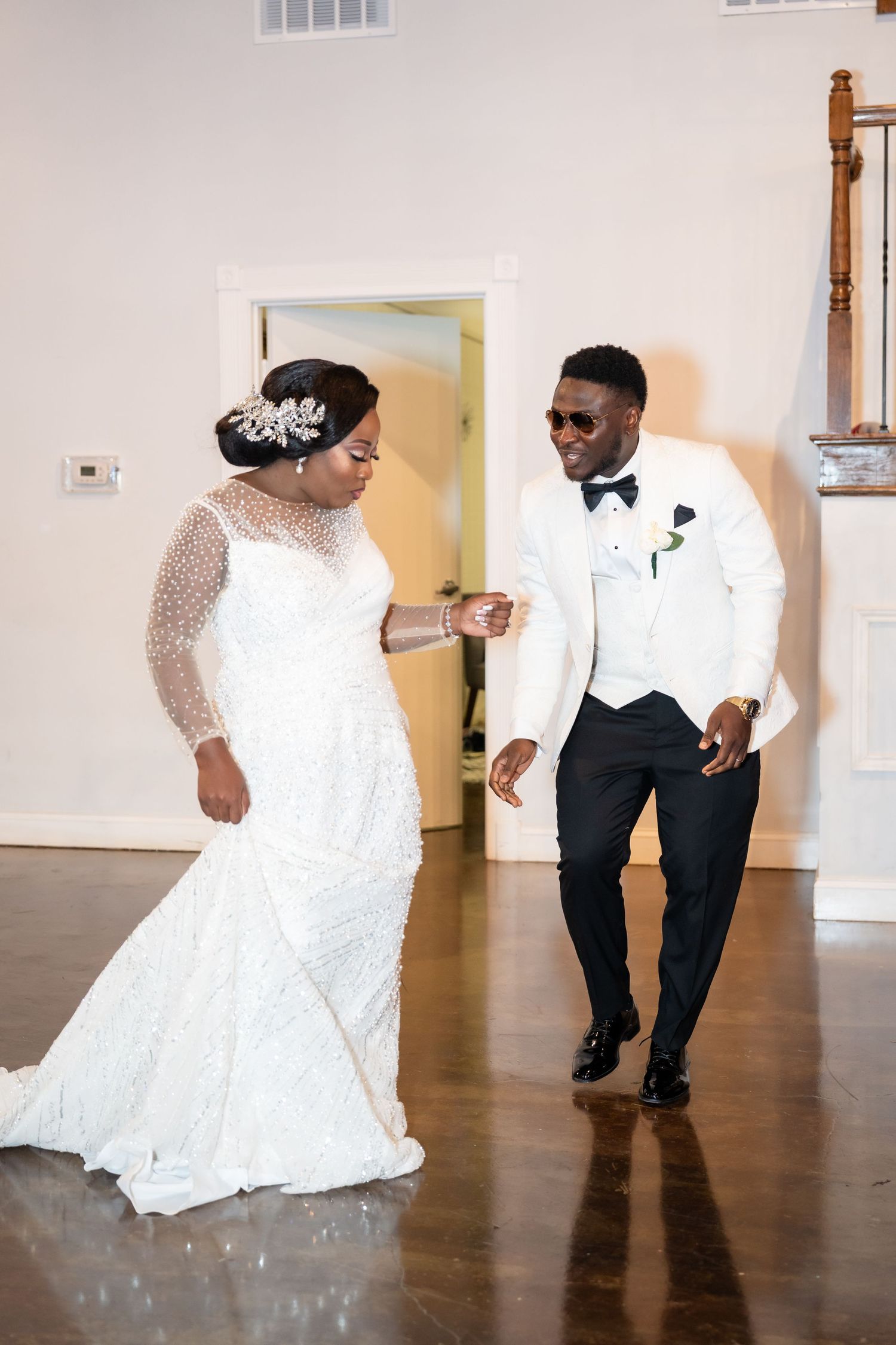 Wedding couple dancing on hardwood floor with bride wearing a stunning white lace gown.