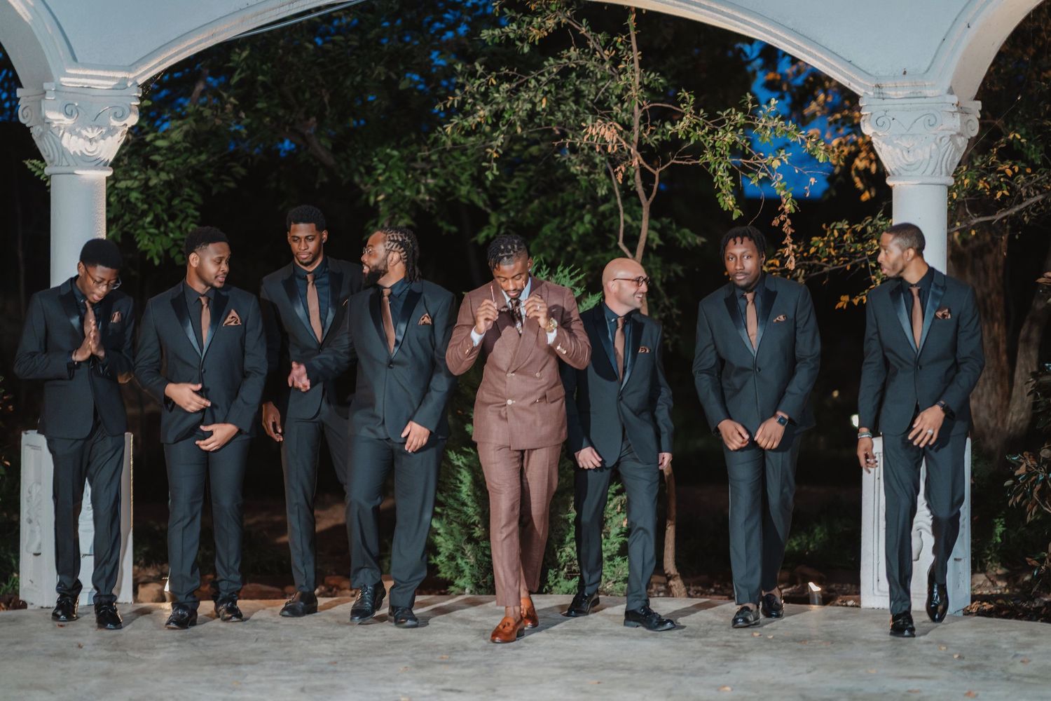 Wedding party members in coordinated attire stand together for a group photo.
