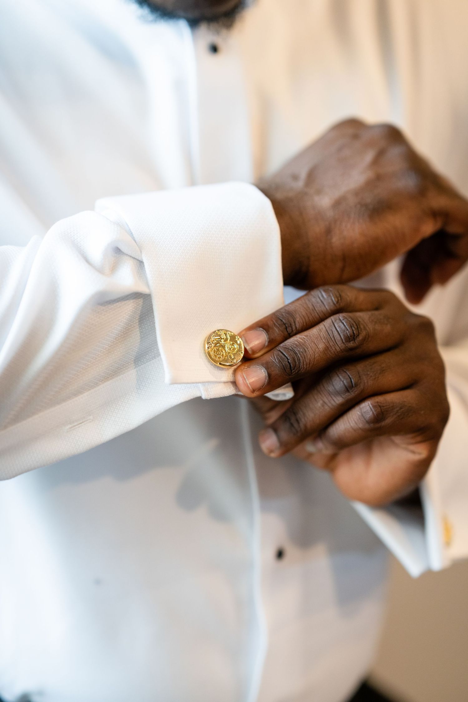 Close-up shots of gold cufflinks being adjusted on a white dress shirt sleeve.