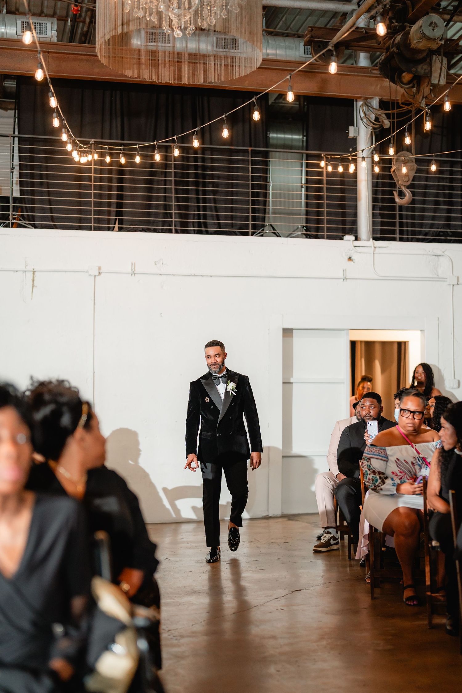 Industrial wedding venue with string lights and wooden details creates modern ambiance.