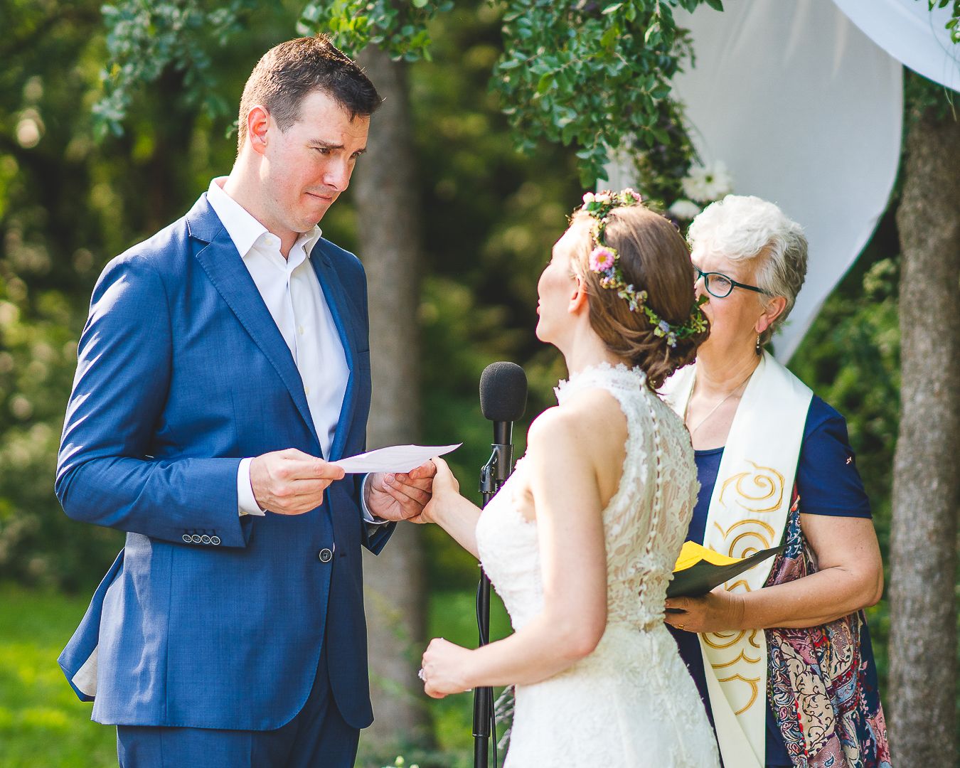 A couple shares an emotional moment during their outdoor wedding ceremony among guests.
