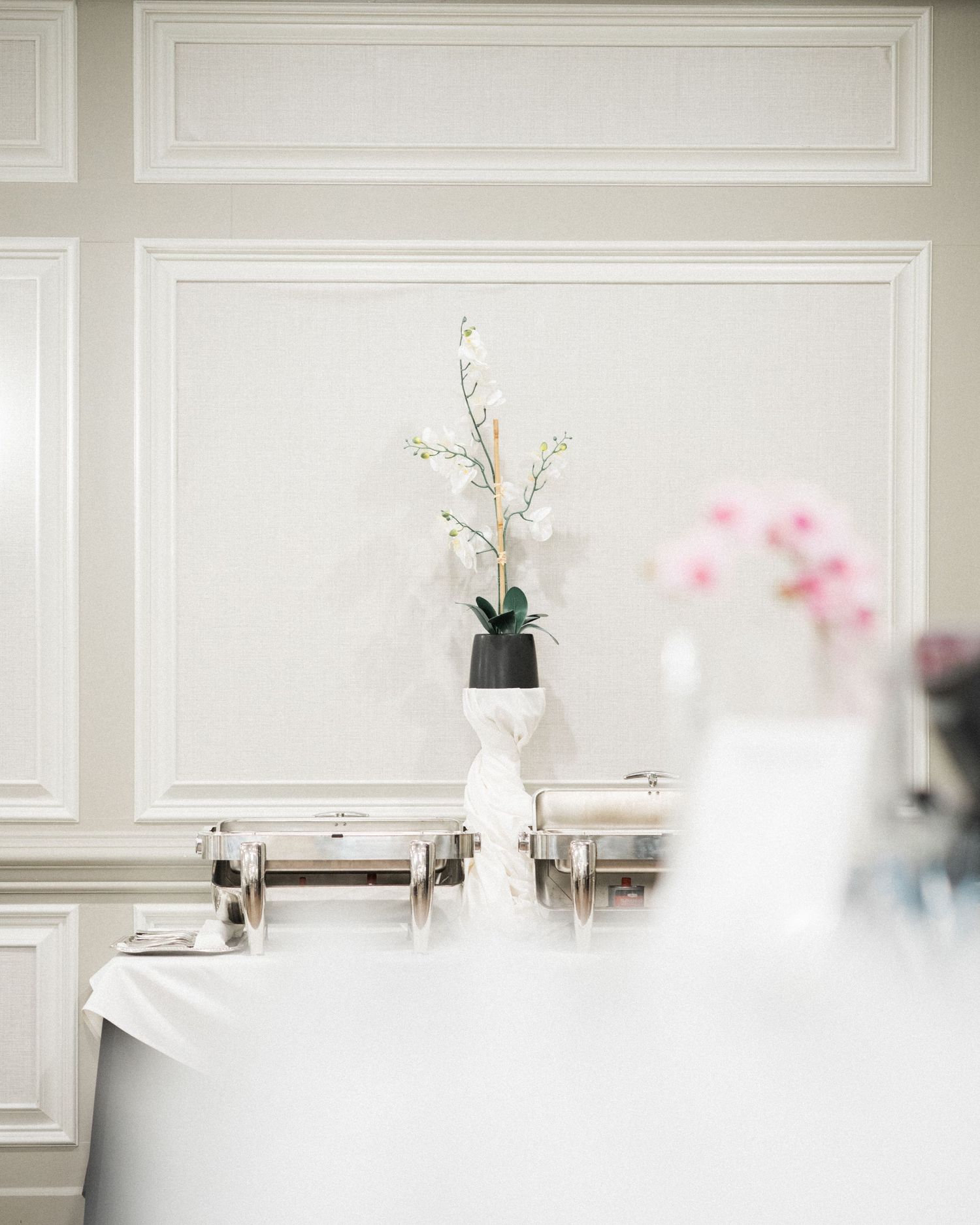 Elegant white wedding reception setup with buffet stations and floral decor.