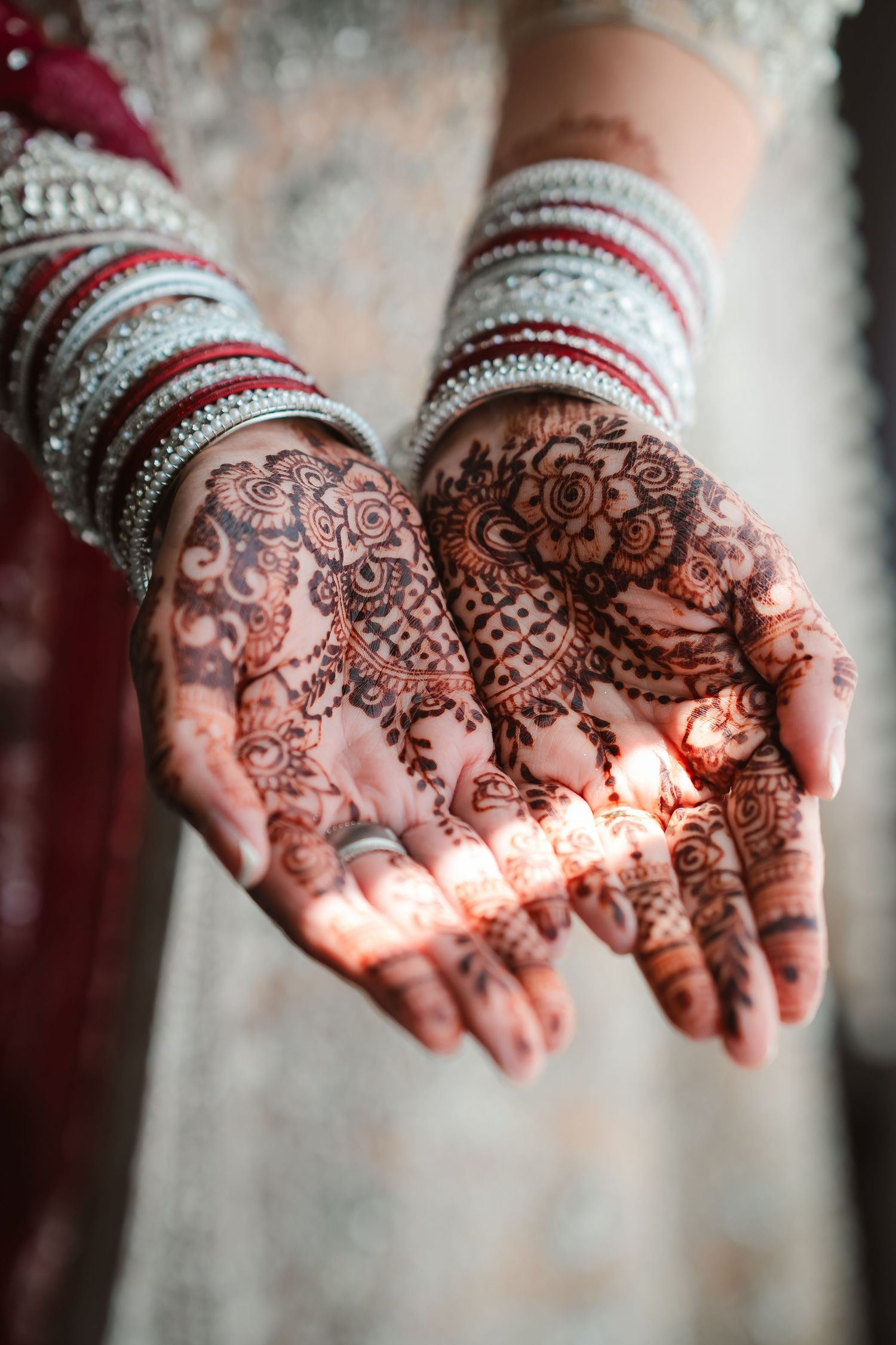 Detailed mehndi henna designs displayed on palms adorned with traditional bangles.