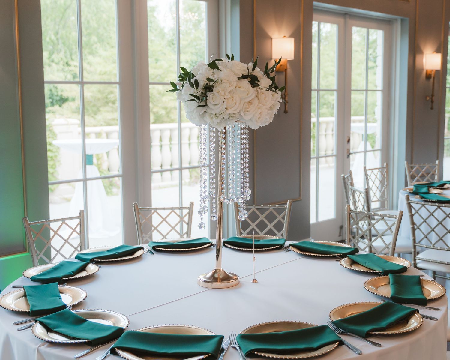 Elegant reception table setting with emerald green chargers and crystal centerpieces.