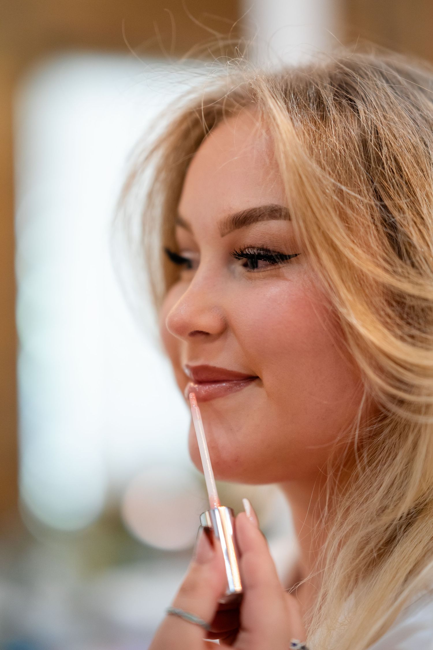 Close-up shots of makeup application with lip gloss being applied.