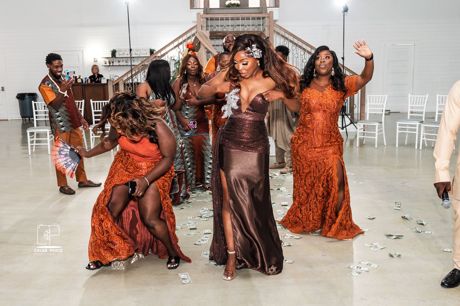 Wedding celebration with guests in orange and brown attire dancing and celebrating.