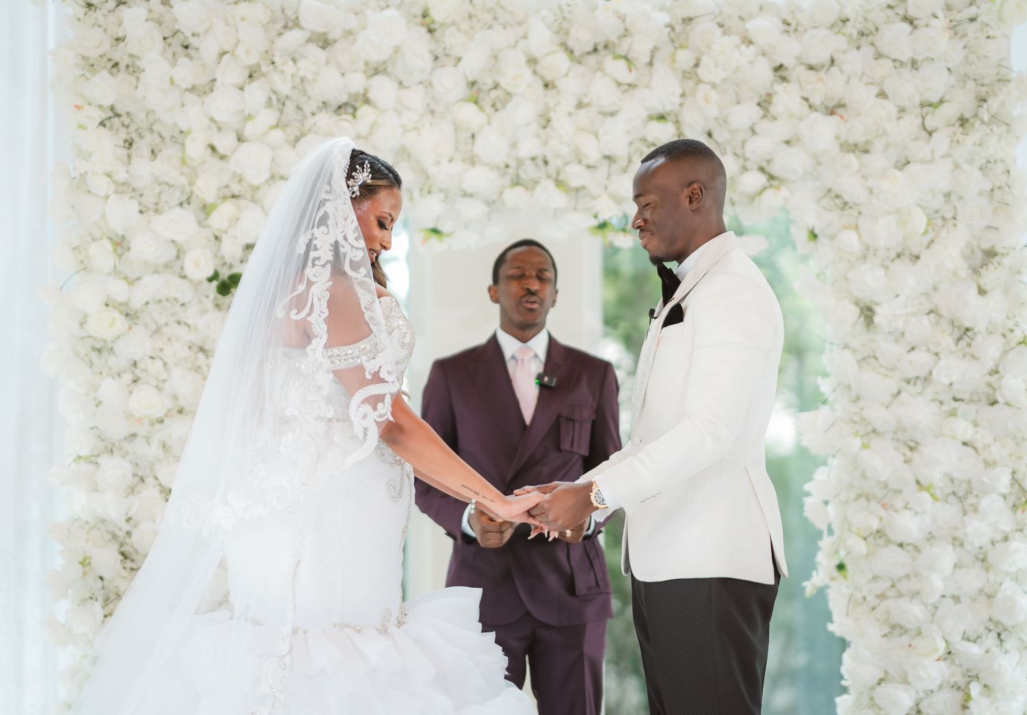 Wedding ceremony setup with white floral wall backdrop and guests seated in rows.