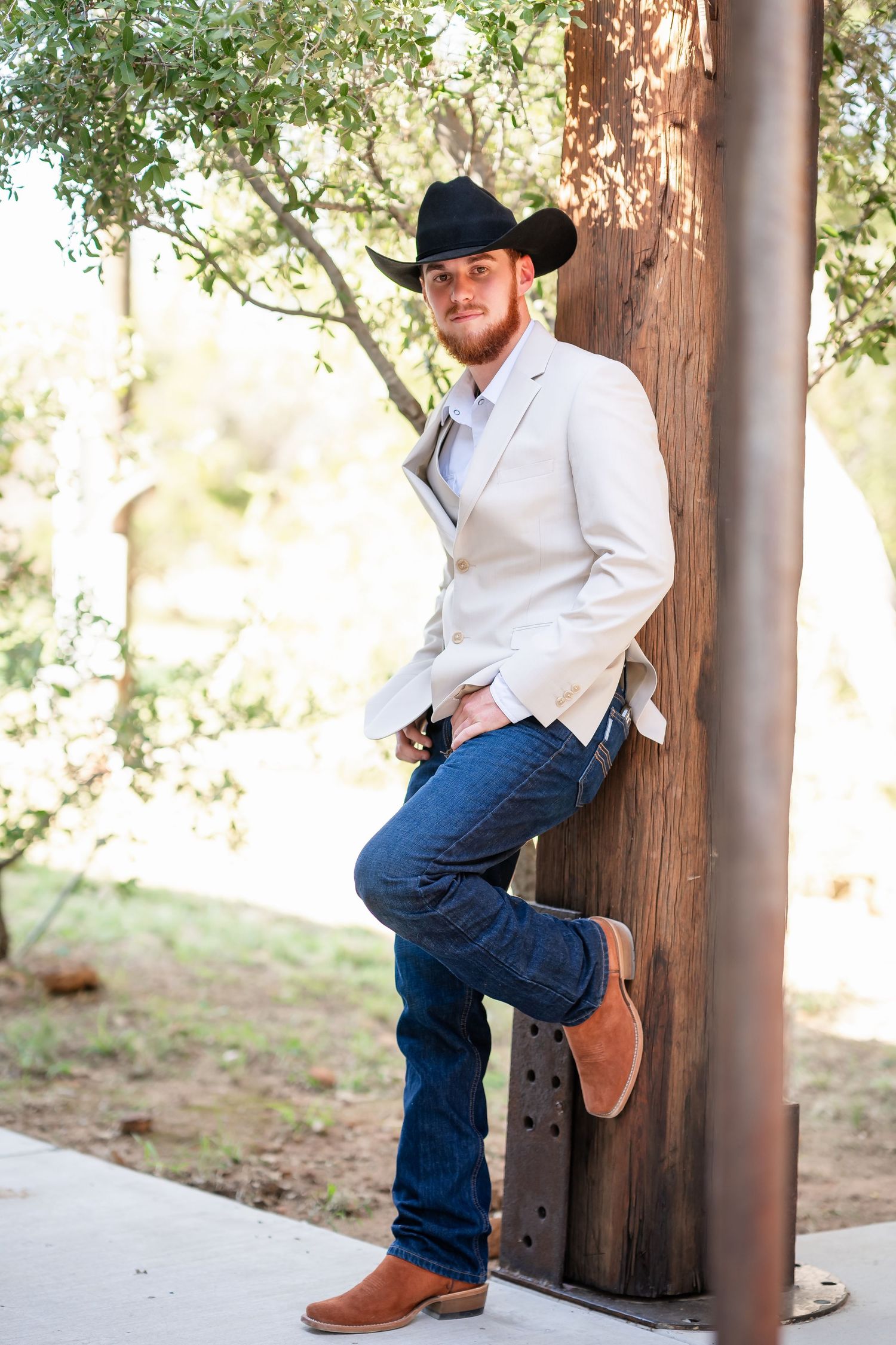 Cowboy boots and jeans shown against wooden posts in a rustic outdoor setting.