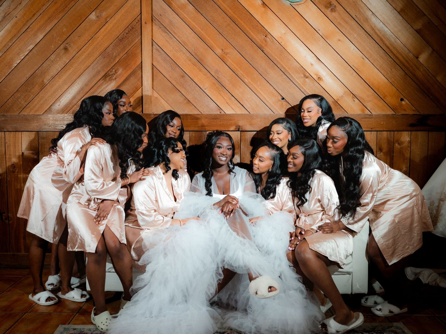 Wedding party having fun and laughing together against rustic wooden wall backdrop.