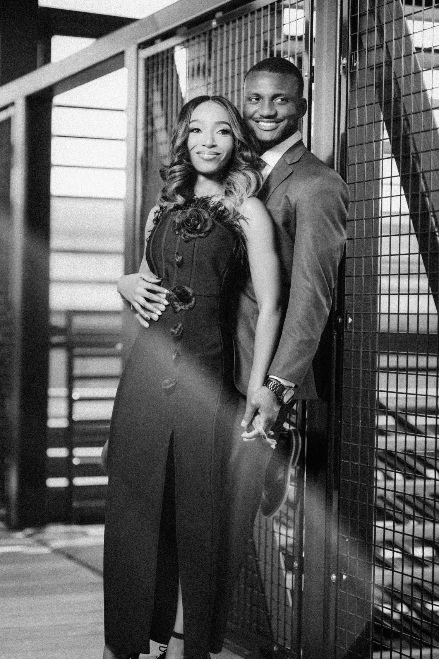 A romantic black and white engagement photo series showing a couple posing together against an industrial backdrop.