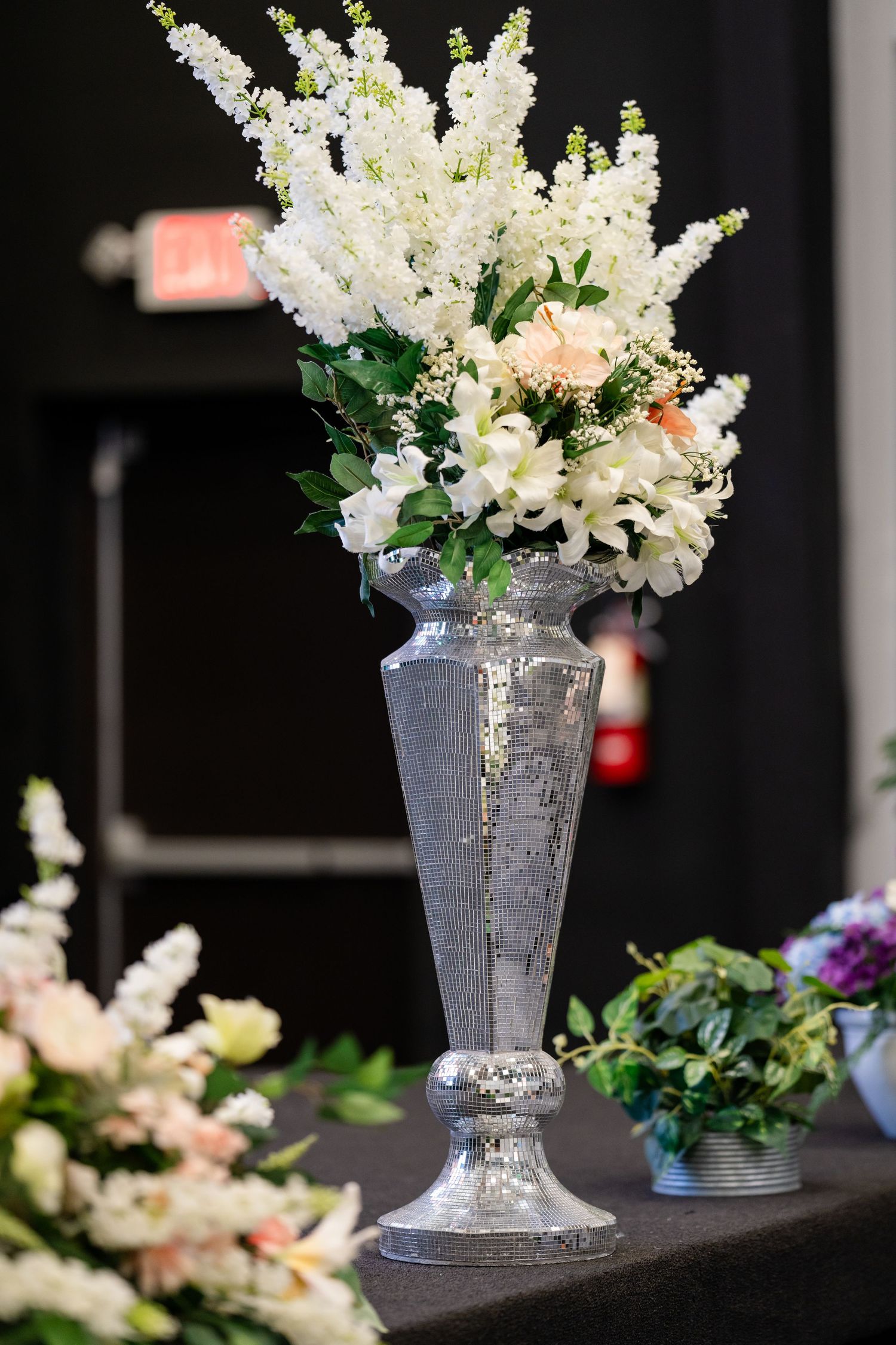 Elegant white floral arrangements in silver vases create a sophisticated display against a dark background.