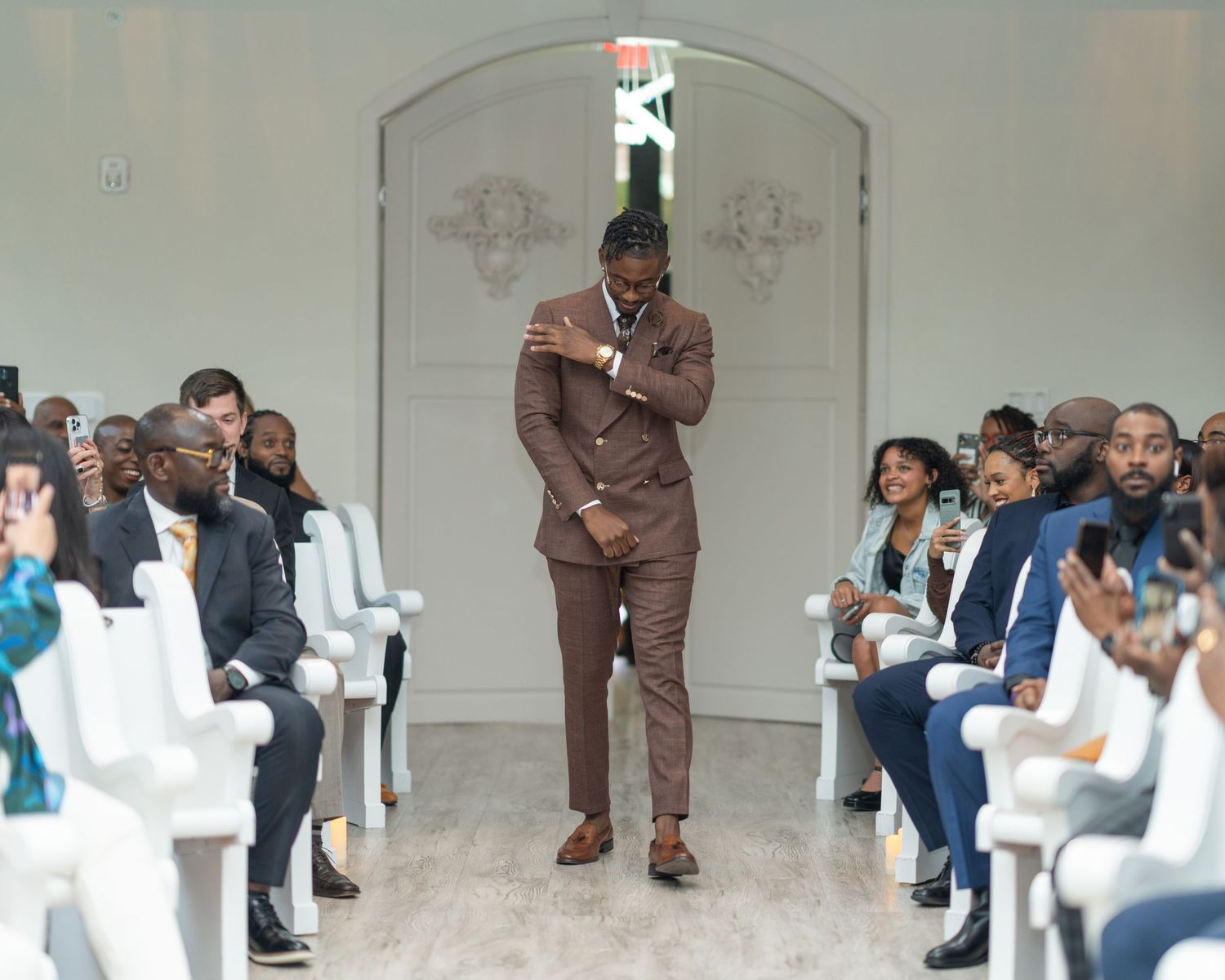 Wedding ceremony setup with white chairs and guests in an elegant indoor venue.