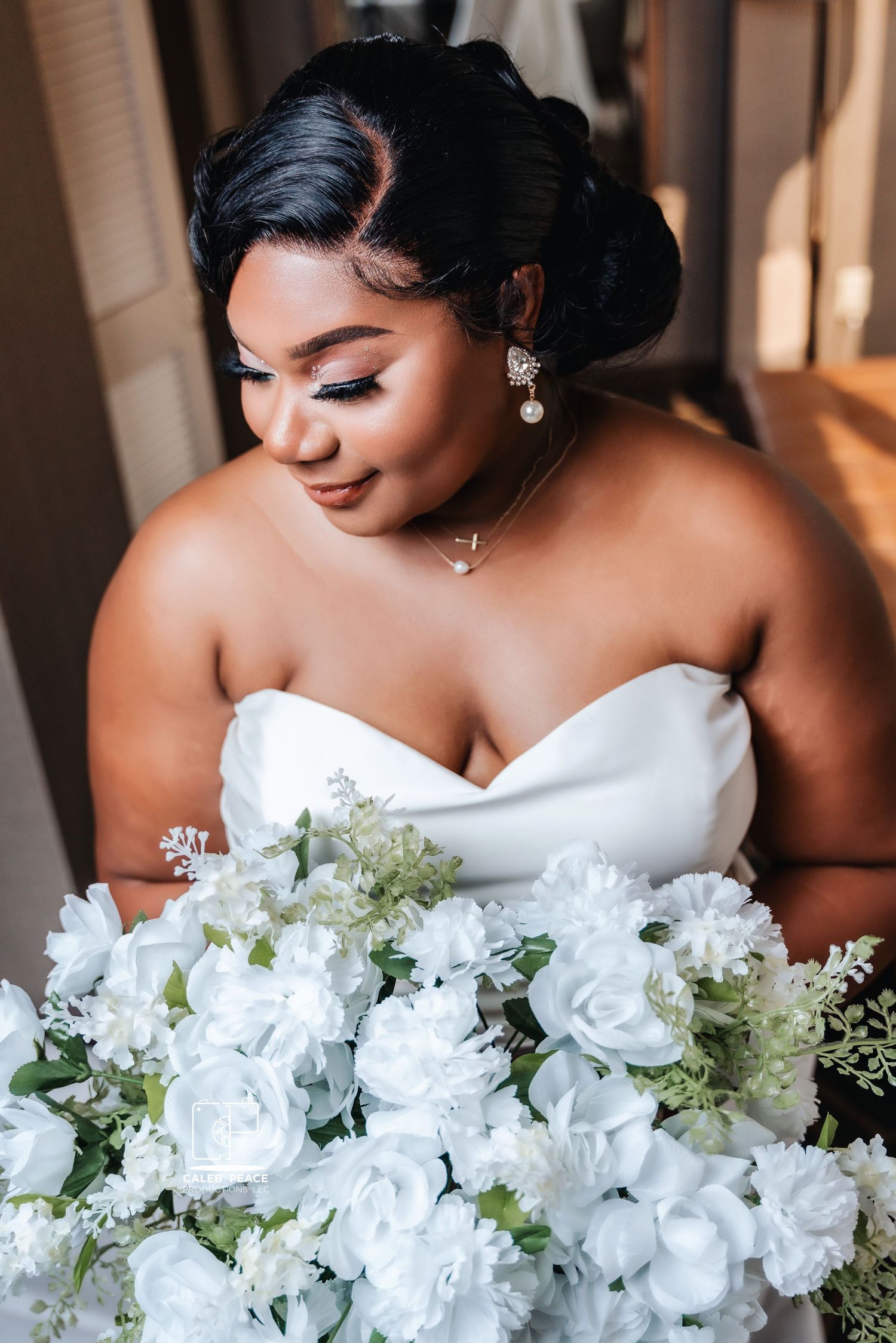 Beautiful white bridal bouquet with roses and greenery against a strapless wedding dress.