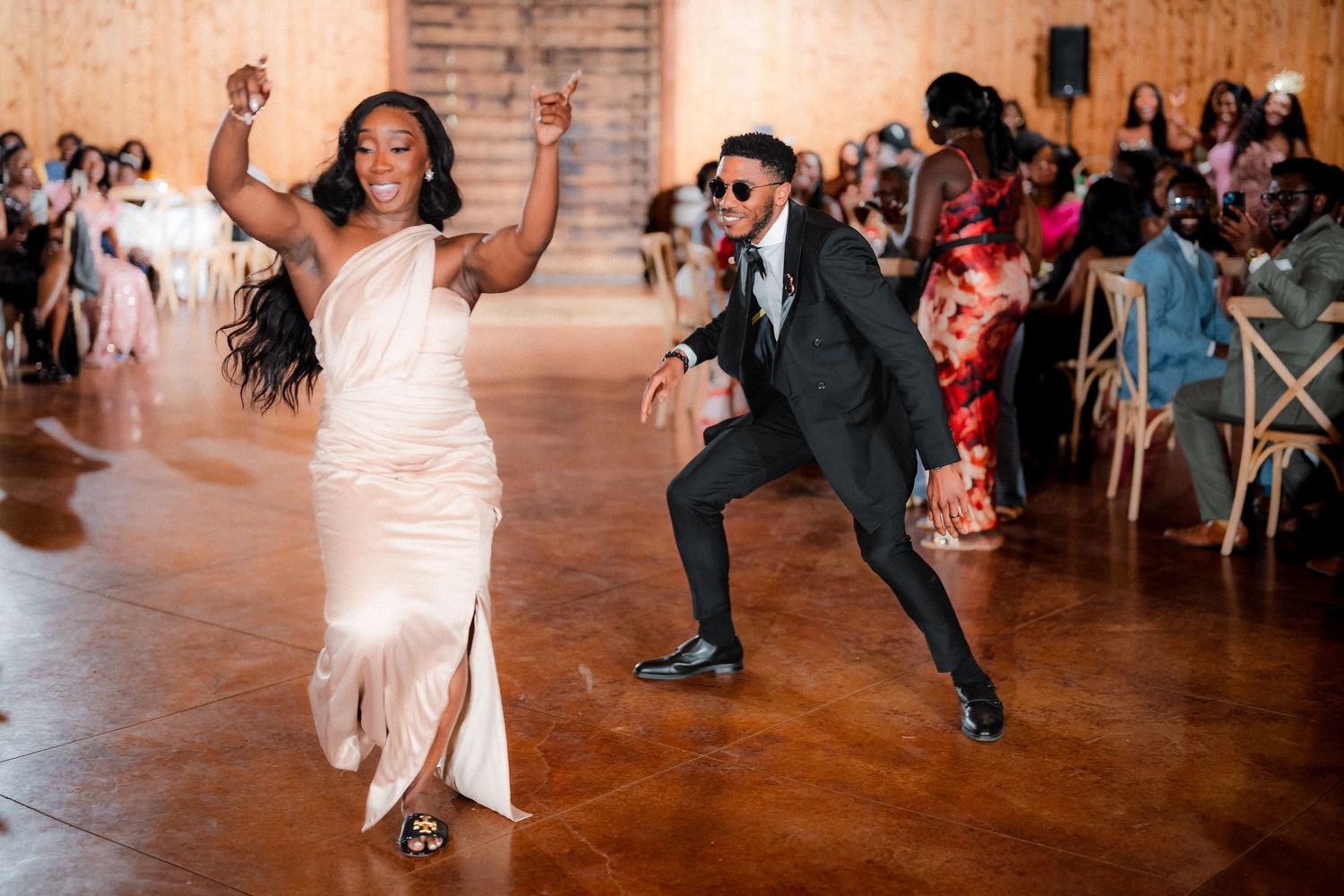 Wedding guests dancing and celebrating with the newlyweds on a rustic wooden dance floor.