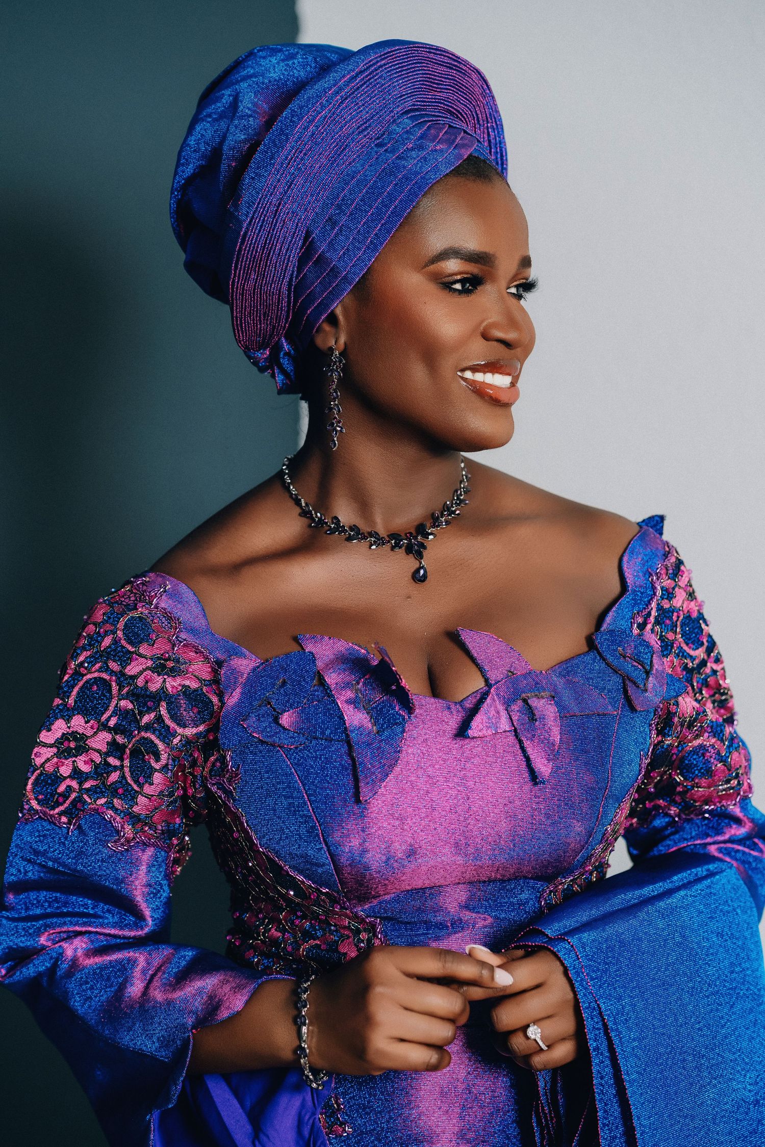 Portrait in vibrant blue and purple traditional African dress with matching gele headwrap and jewelry.
