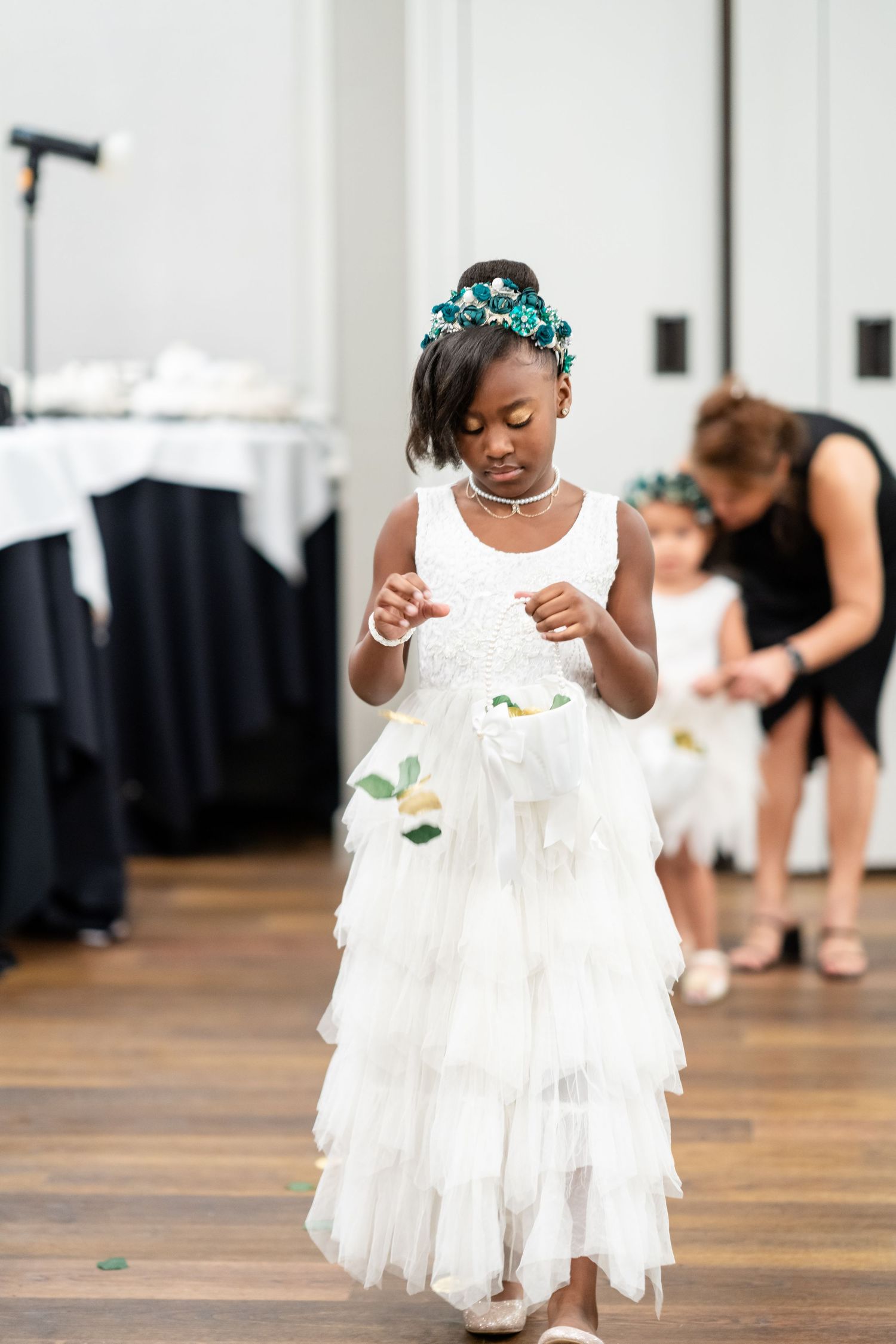 Young flower girls in white tulle dresses dancing on hardwood floors.