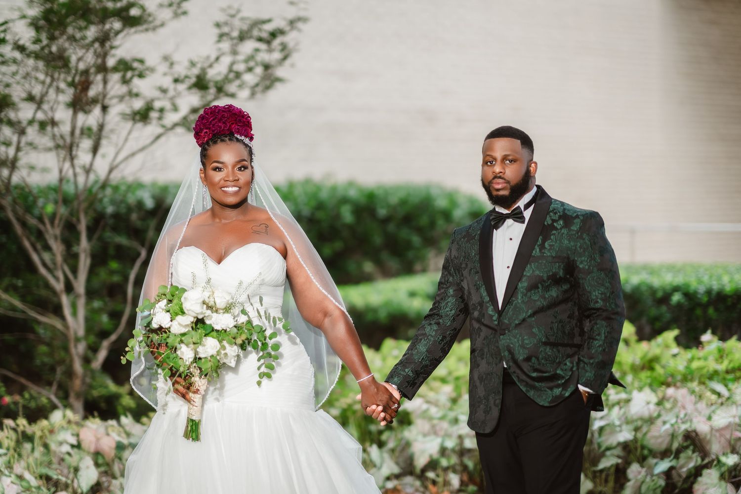 Outdoor wedding portraits with greenery and white brick architectural backdrop.