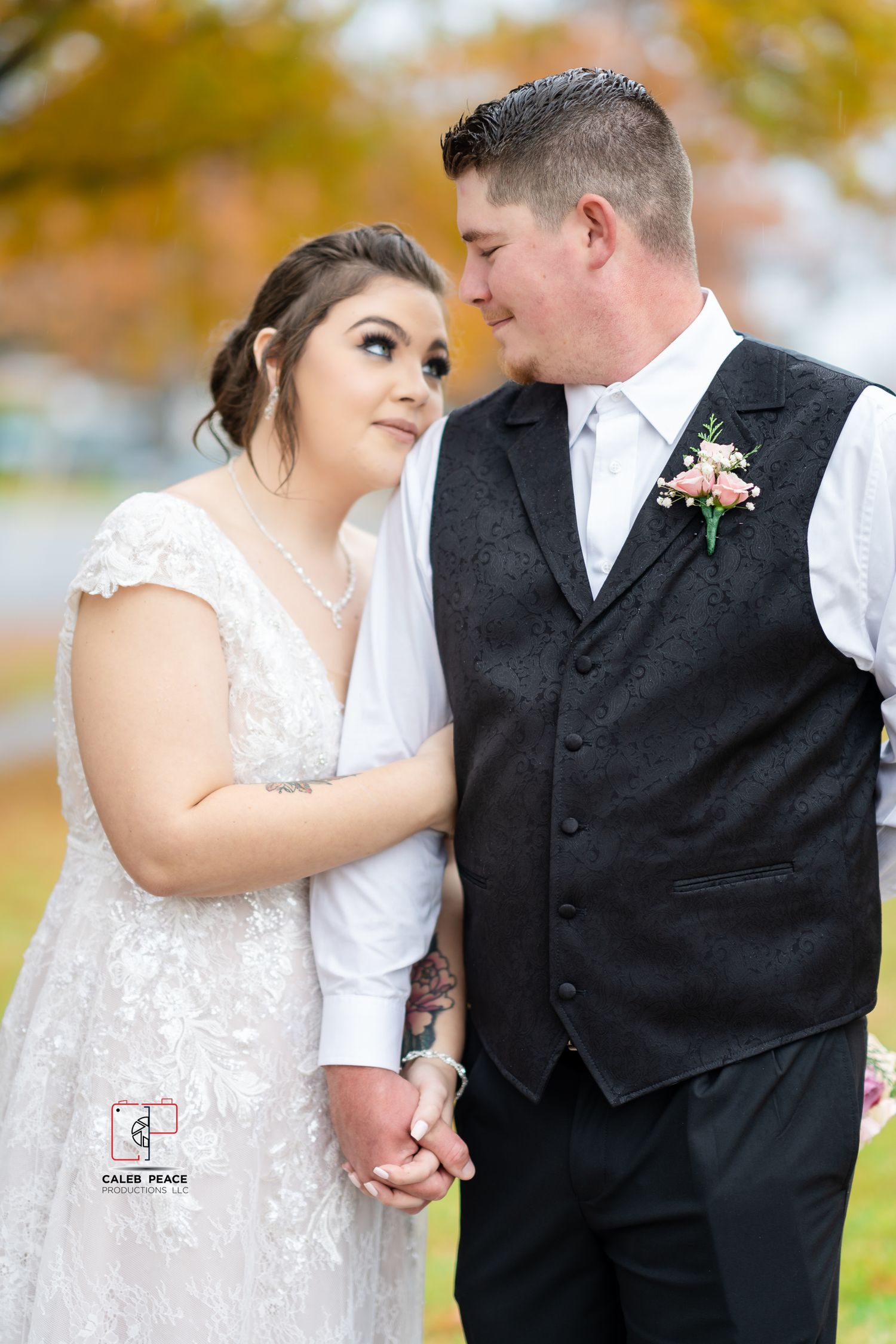 A couple shares intimate moments in their wedding attire during a fall photoshoot with autumn foliage in the background.
