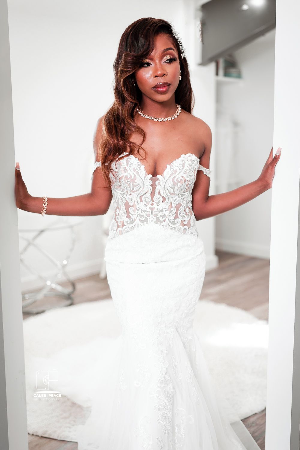 Beautiful bride poses in elegant white lace wedding gown with strapless sweetheart neckline in bright studio setting.