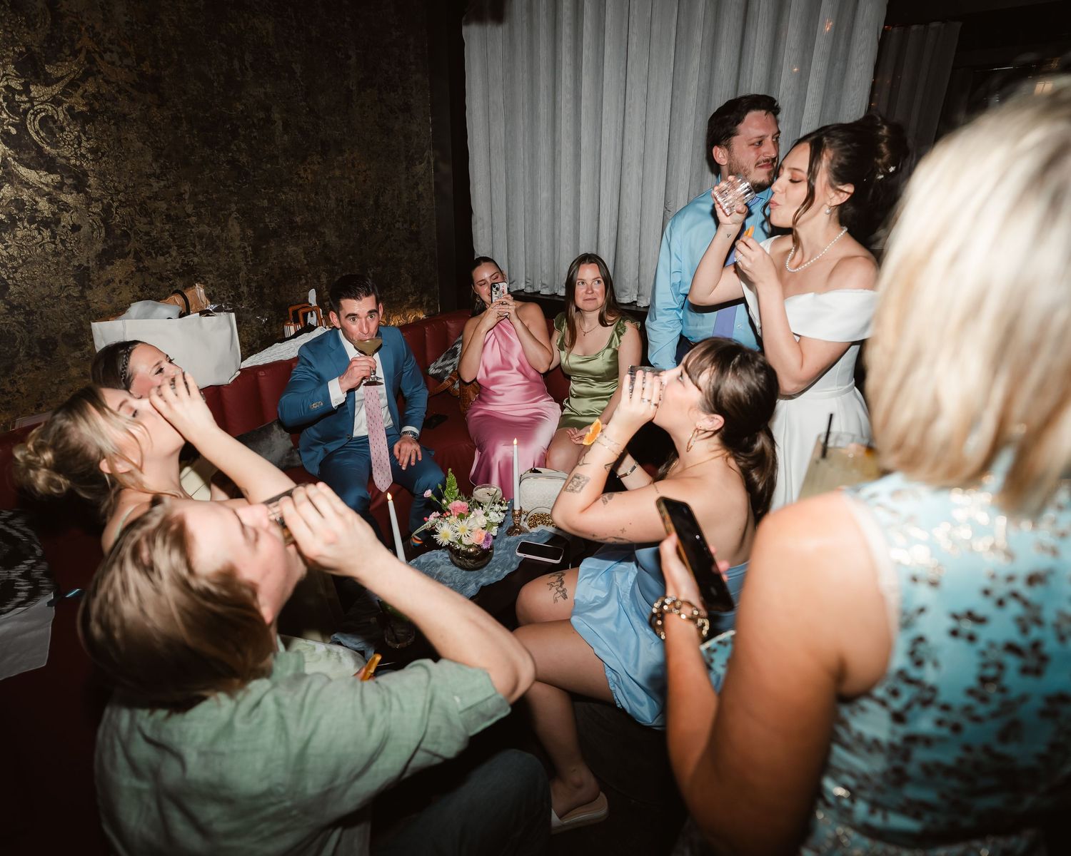 Wedding reception guests dancing energetically in a dimly lit venue.